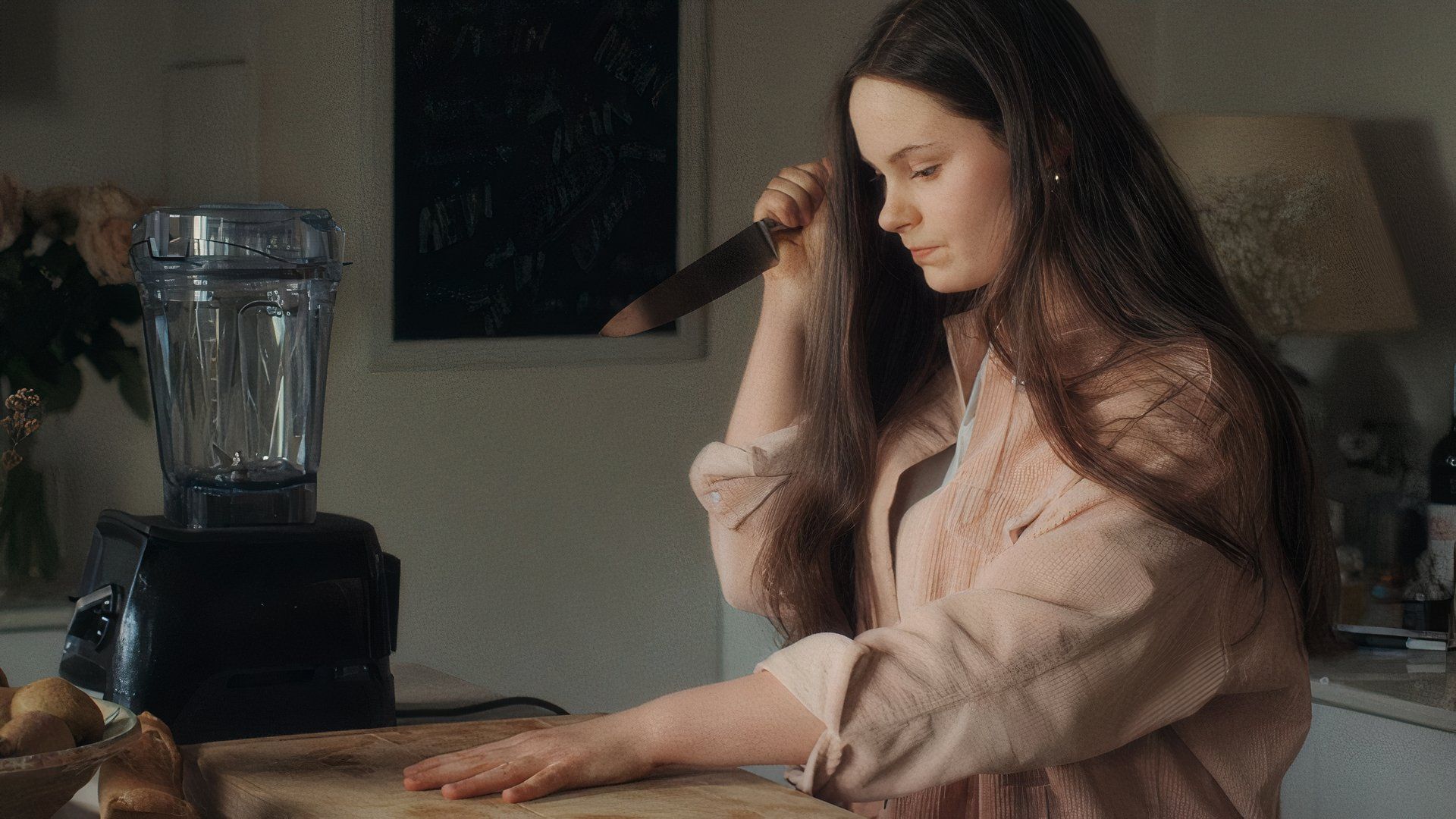 Louise Labèque as The Teenager in Coma, preparing to stab her own hand with a kitchen knife