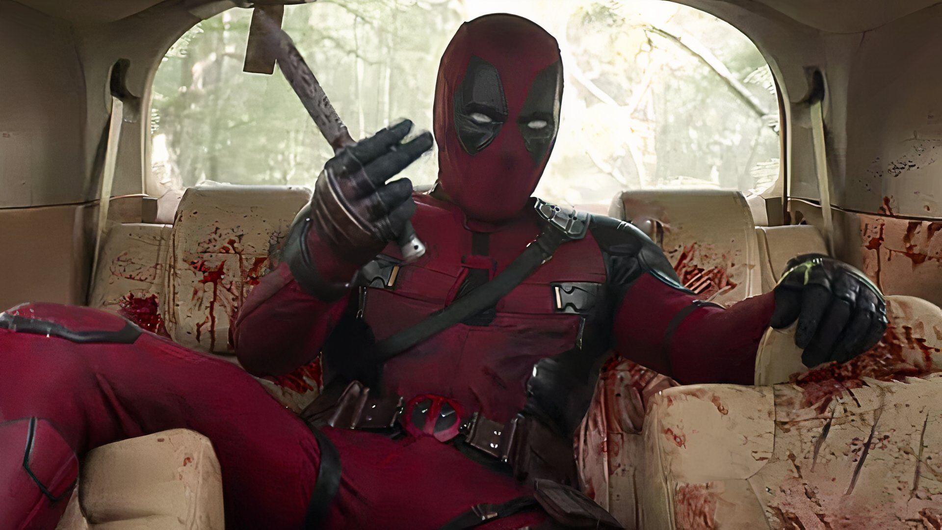 Deadpool surrounded by blood in the back of a car.