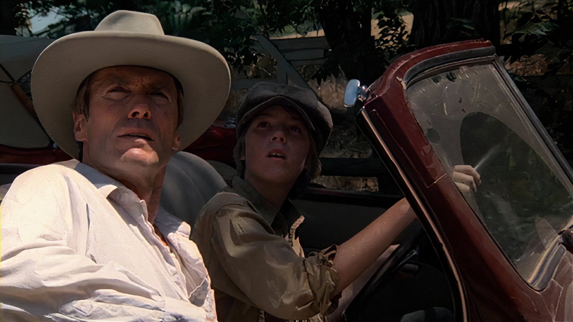 Clint Eastwood with Kyle Eastwood driving in a convertible car looking up off-screen in Honkytonk Man