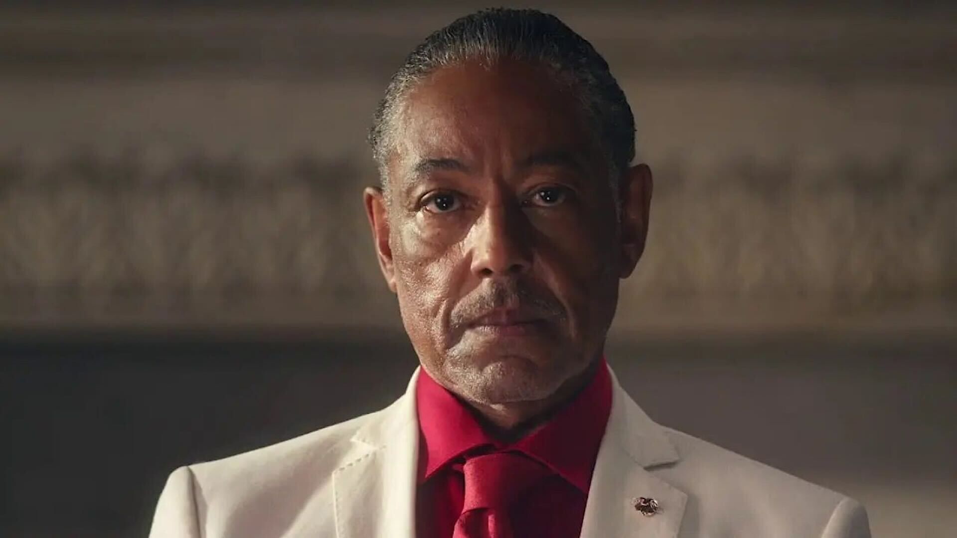 Giancarlo Esposito looking serious with red shirt and tie