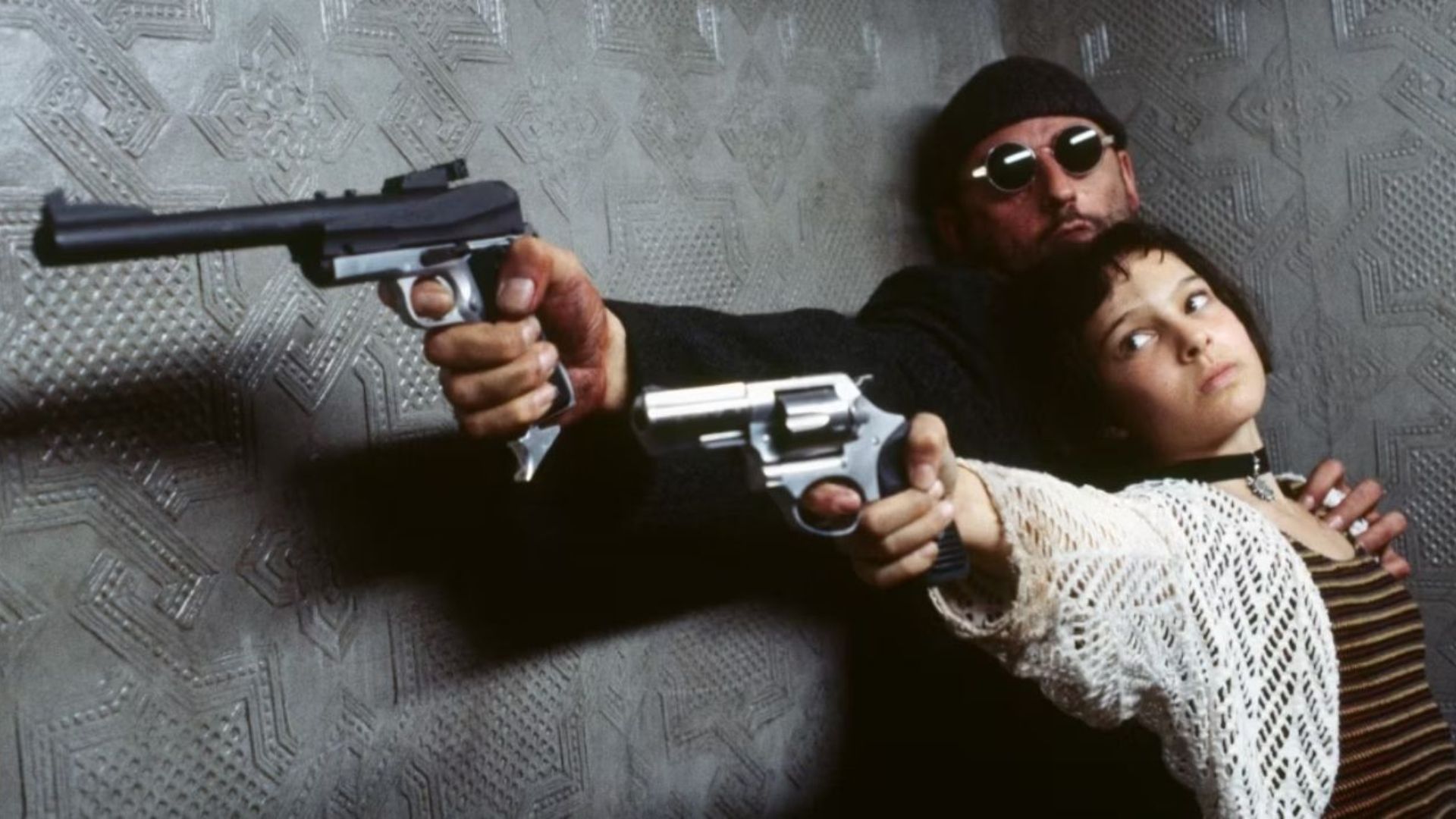 Jean Reno as Leon and Natalie Portman as Mathilda pointing guns together in Léon: The Professional