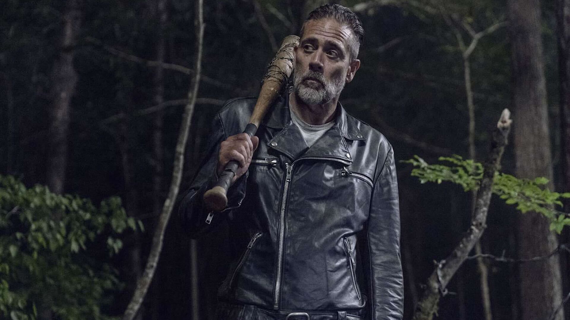 Jeffrey Dean Morgan as Negan holding Lucille over his right shoulder in a forest