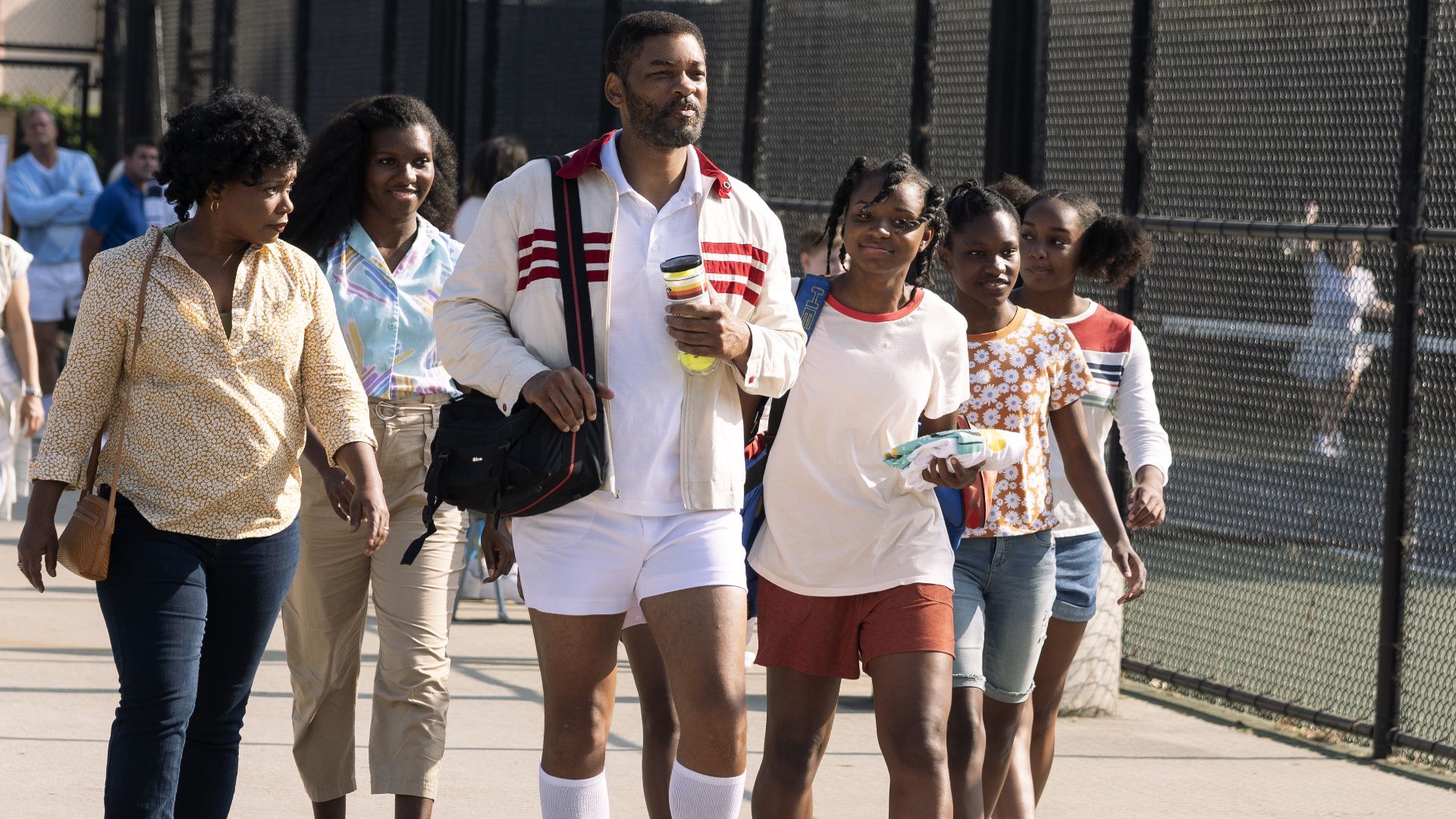 The Williams family walks by a tennis court in King Richard