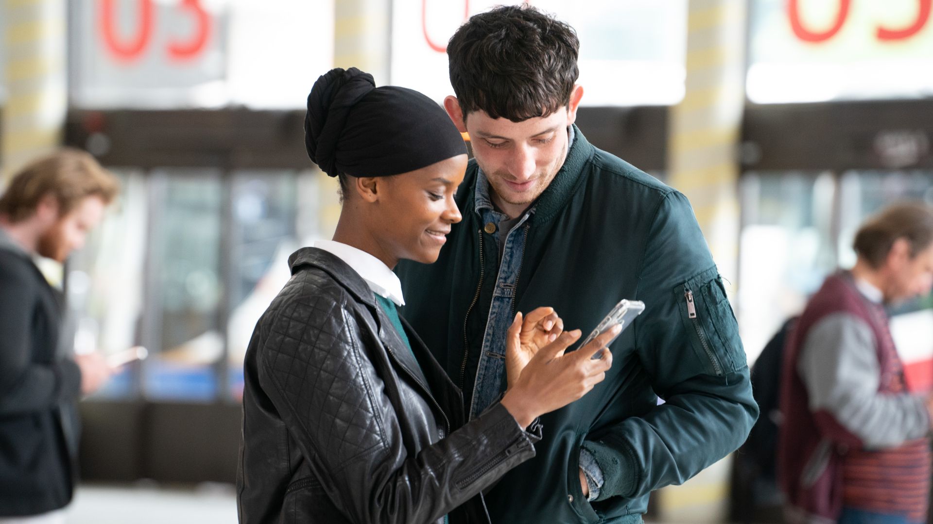 Letitia Wright and Josh O'Connor look at a phone in the 2024 movie Aisha