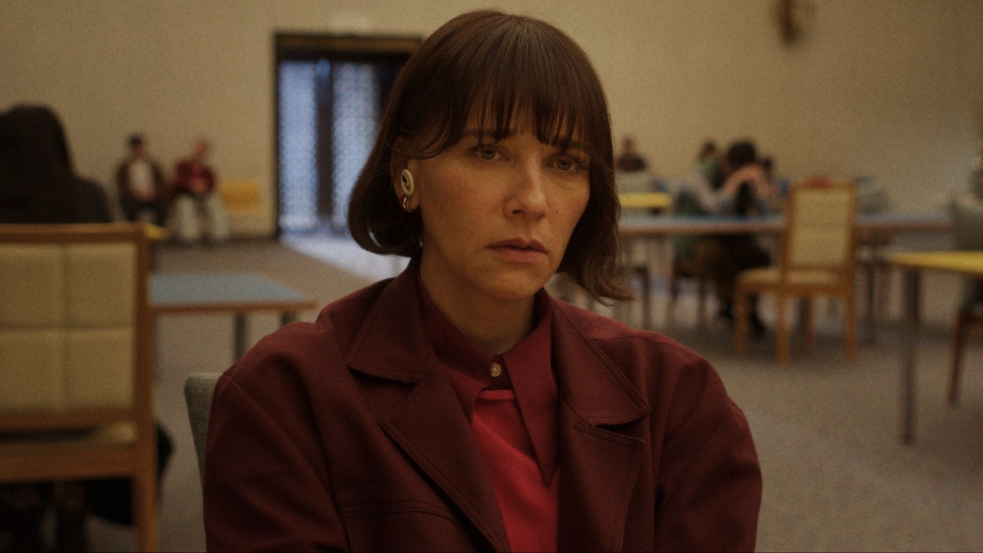 Rashida Jones in a red trench coat with a worried expression as Suzie in Sunny