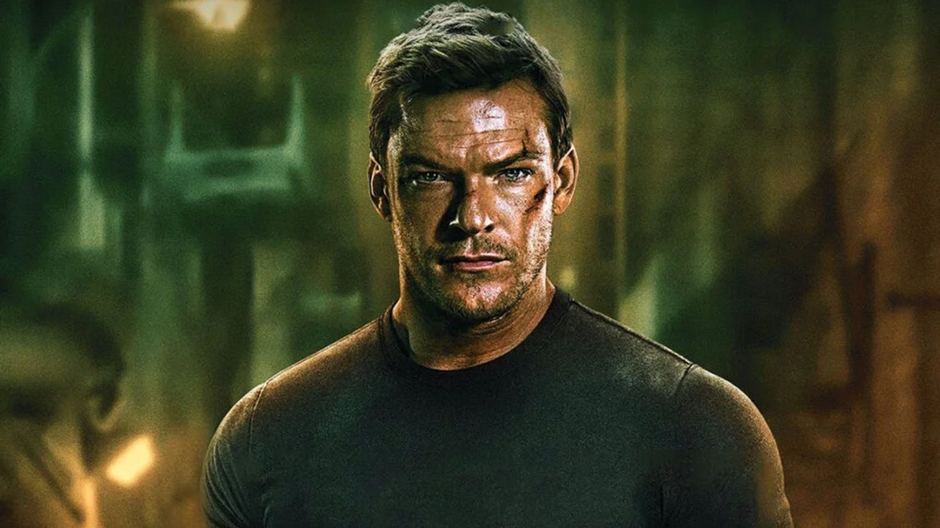 Alan Ritchson as Jack Reacher wearing a dark t-shirt with cuts on his face