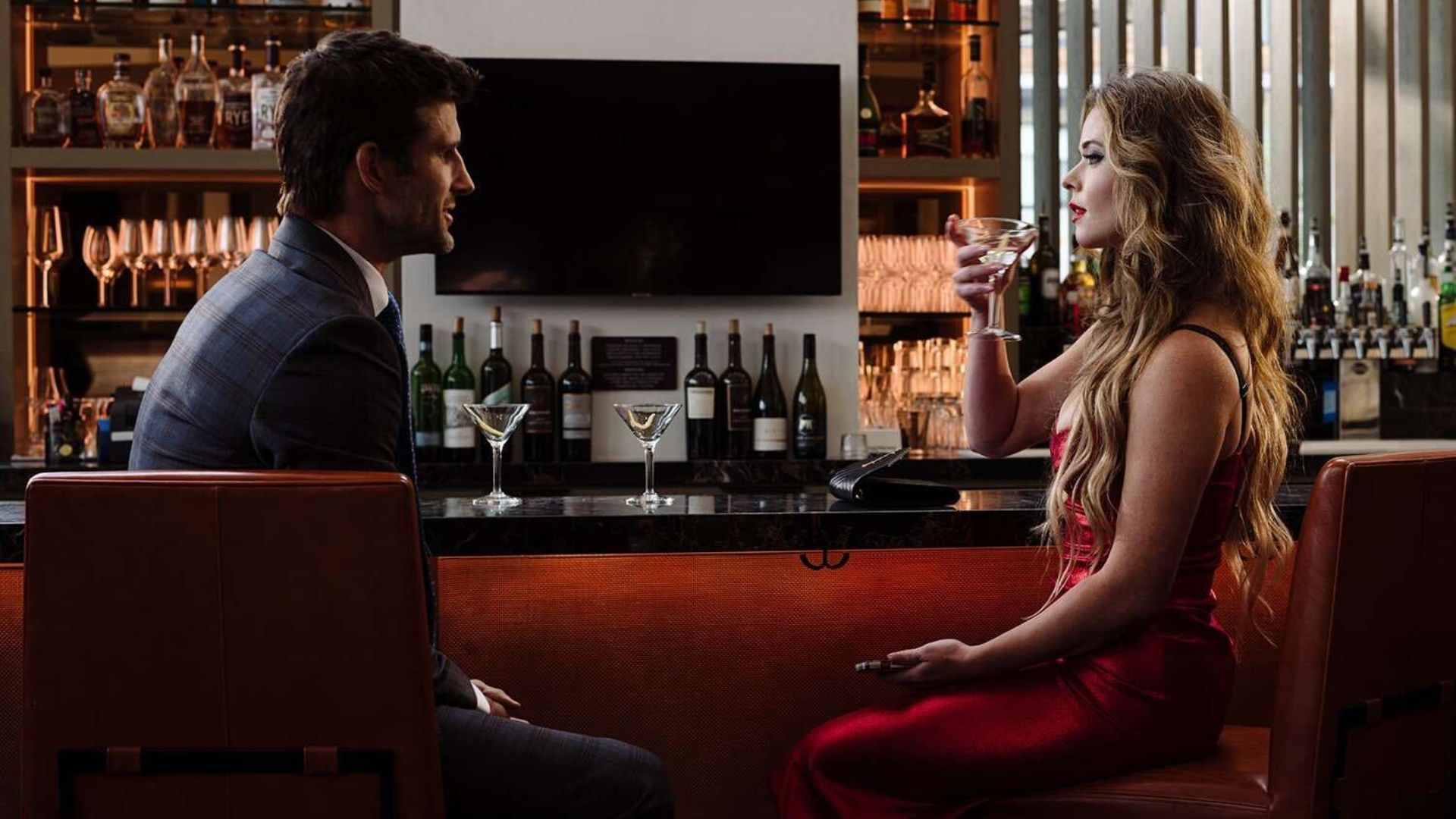 Sasha Pieterse and Parker Young sitting at a bar drinking and talking in The Image of You