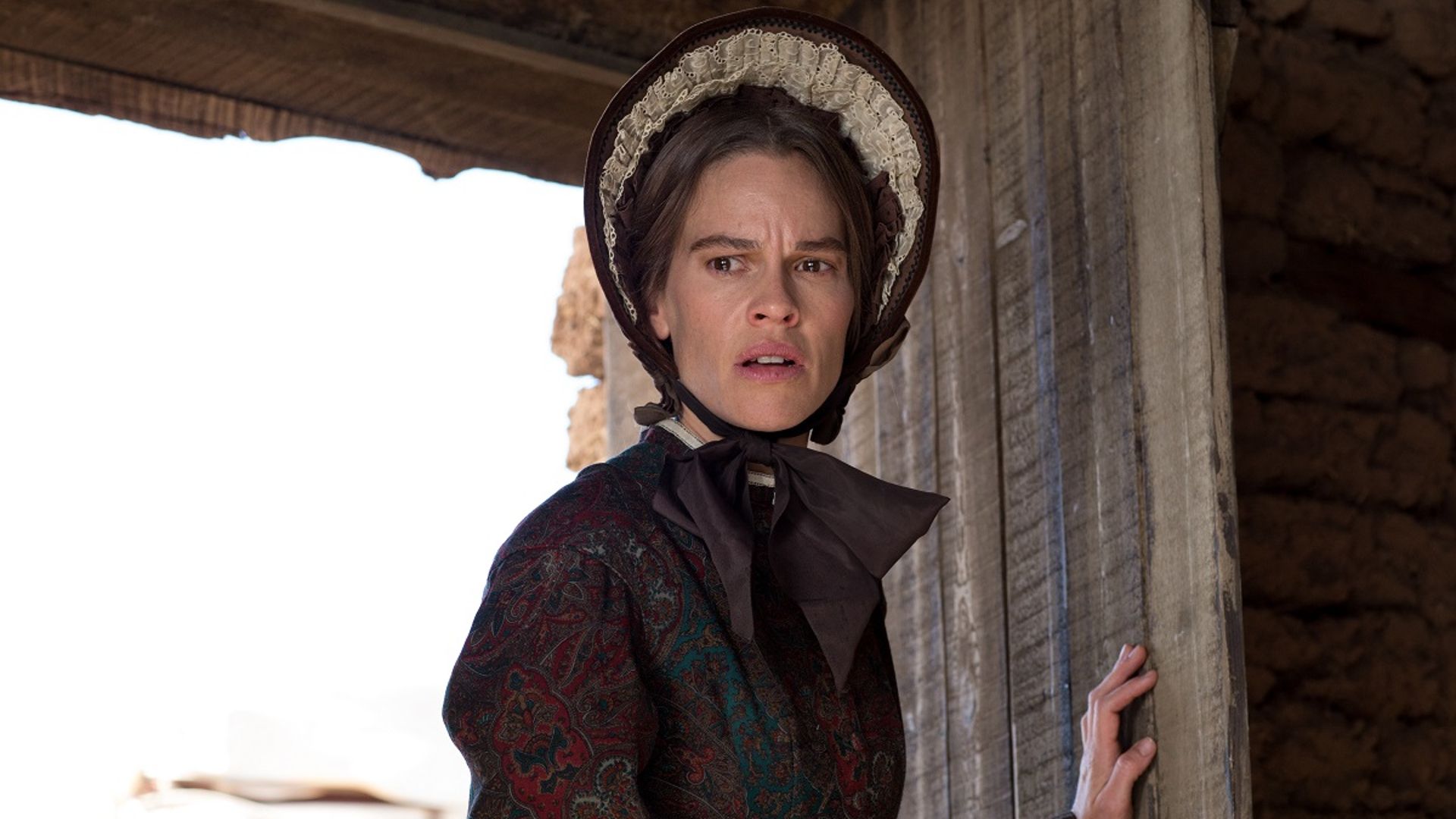 Mary stands in a doorway in The Homesman
