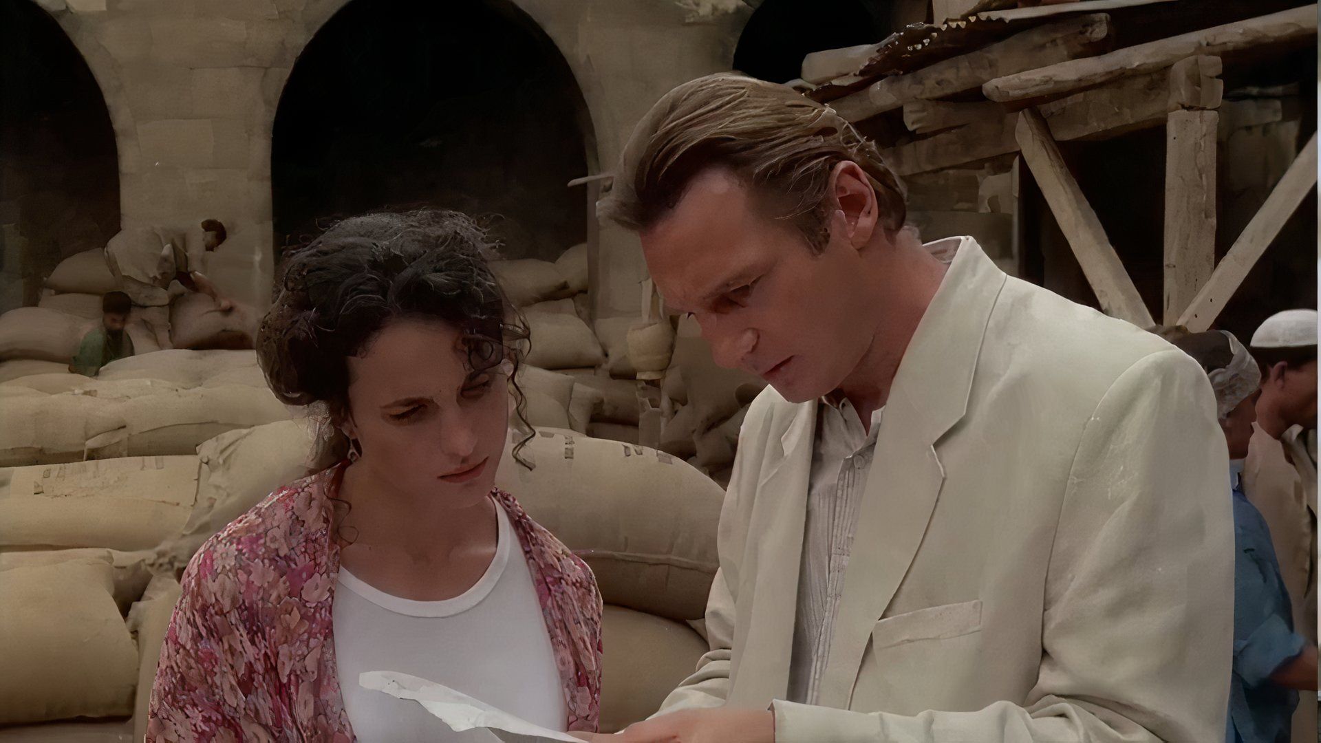 Liam Neeson and Andie MacDowell looking at a paper in the 1992 drama Ruby Cairo