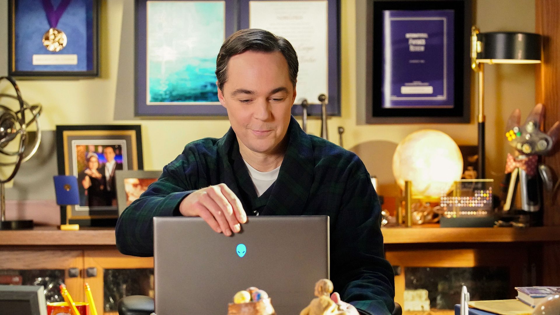 An older Sheldon smiling while opening his laptop on Young Sheldon.