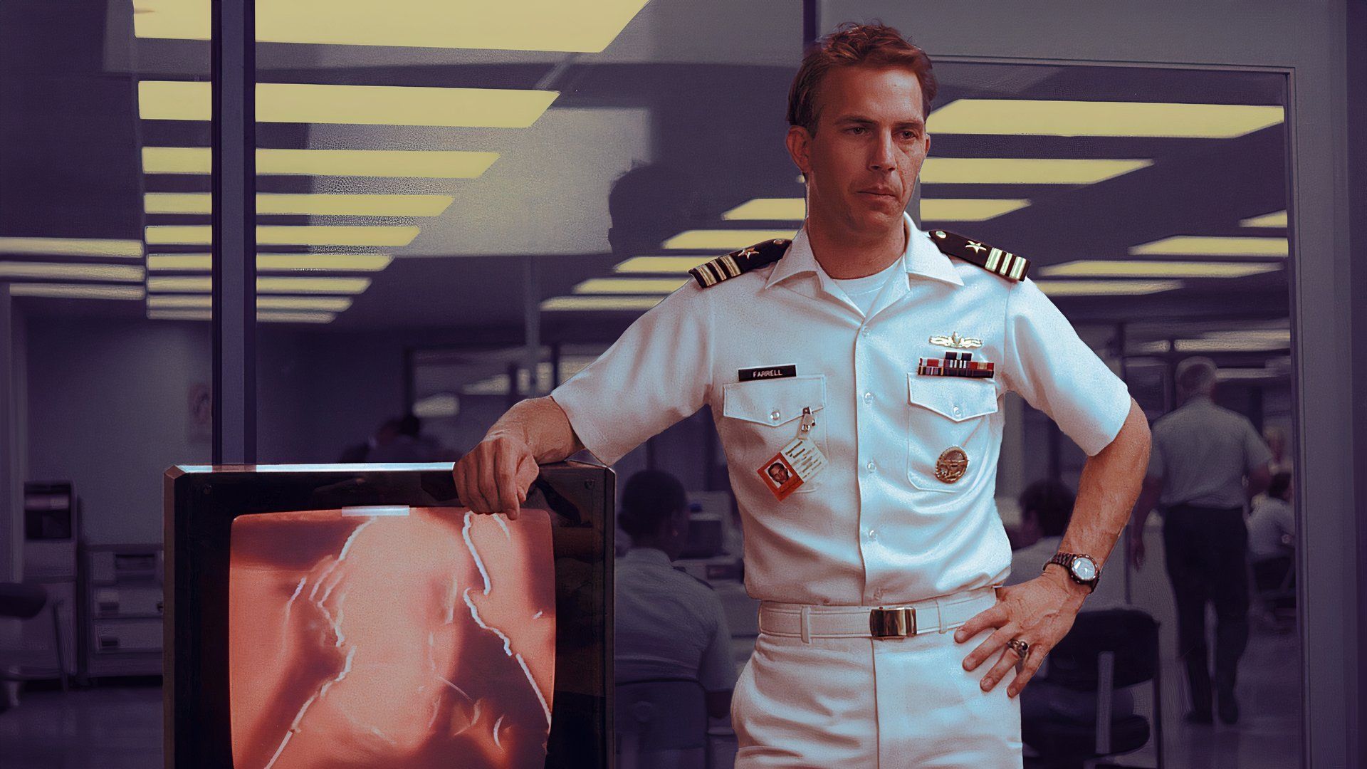 An edited image of Kevin Costner as Lt. Cmdr. Tom Farrel wearing a captain uniform next to a TV screen in No Way Out