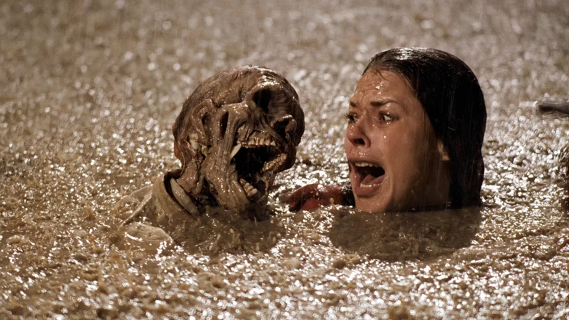 Diane looks scared while in a pool of mud when a skeleton rises up beside her in the film Poltergeist