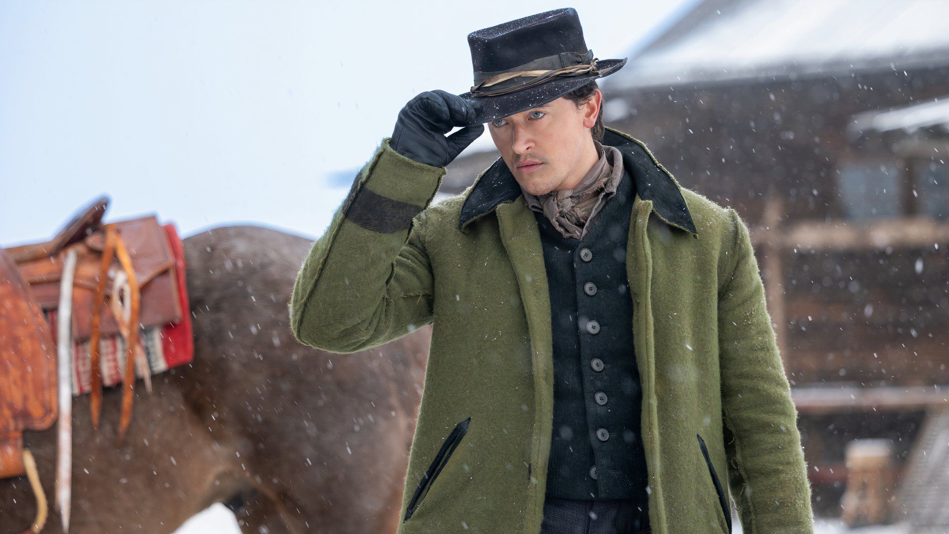 Tom Blyth tips his hat as Billy the Kid in the snow in season two part two