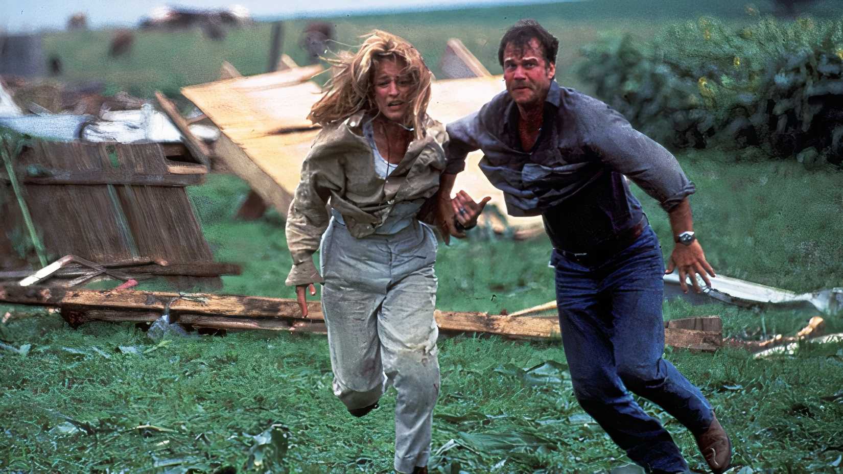 A still featuring a scene with Helen Hunt and Bill Baxton in 1996's Twister running through a field