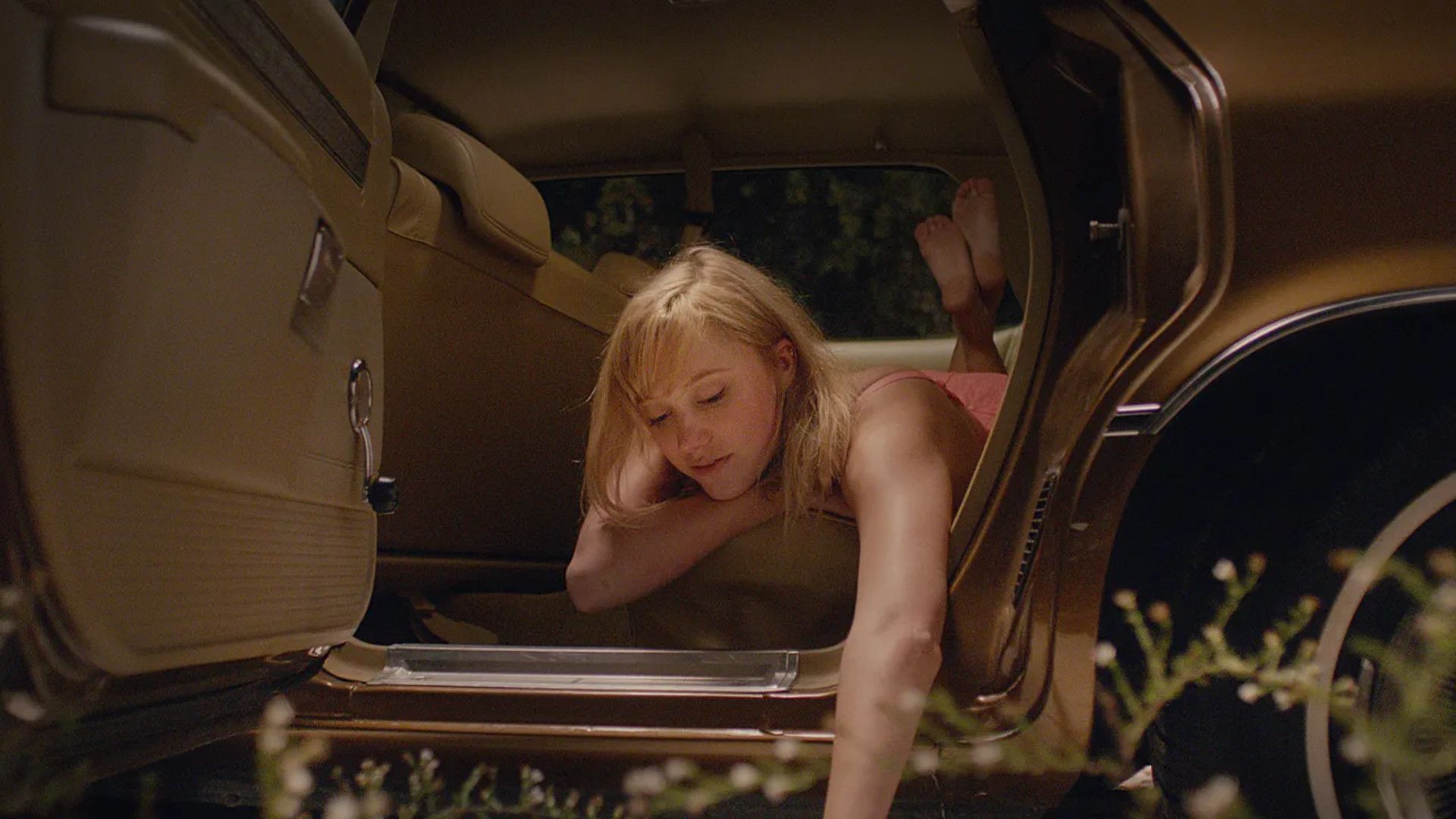 Maika Monroe hangs out of a car in It Follows