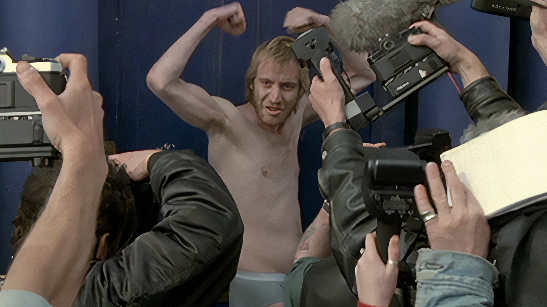 Rhys Ifans as Spike with his shirt off flexing for TV cameras in Notting Hill