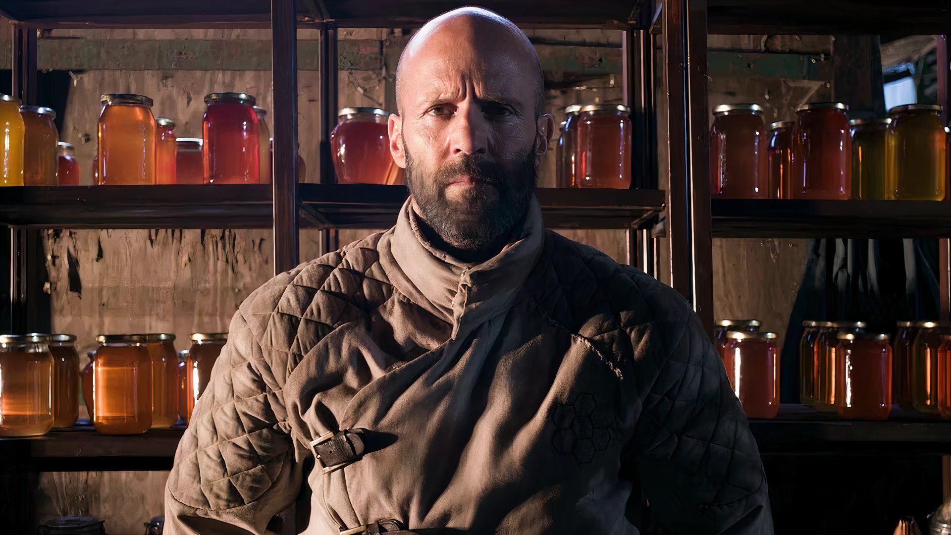 Jason Statham surrounded by honey jars in the film The Beekeeper