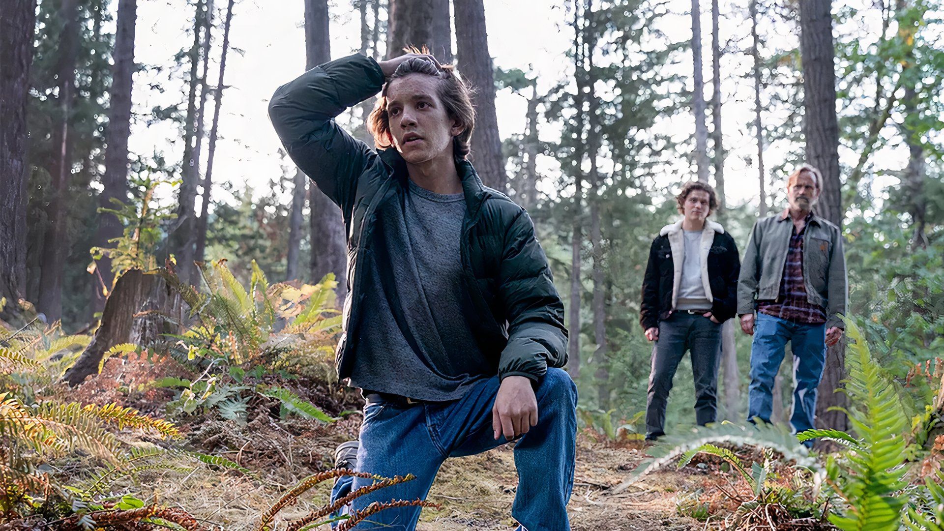 A young Colter kneeling on the ground as his dad and brother look on in a flashback scene in Tracker.