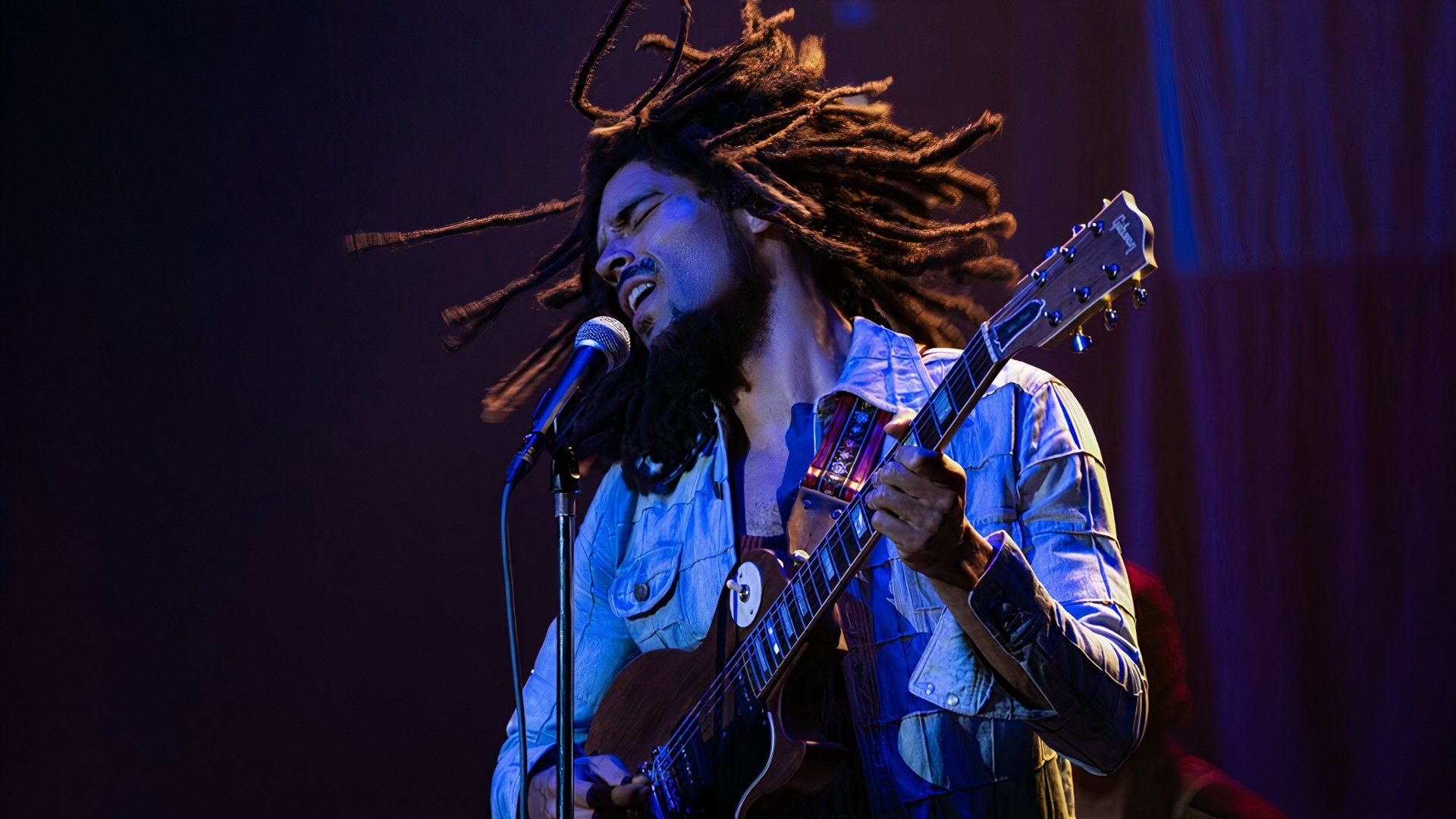 Bob plays guitar on stage in One Love: Bob Marley