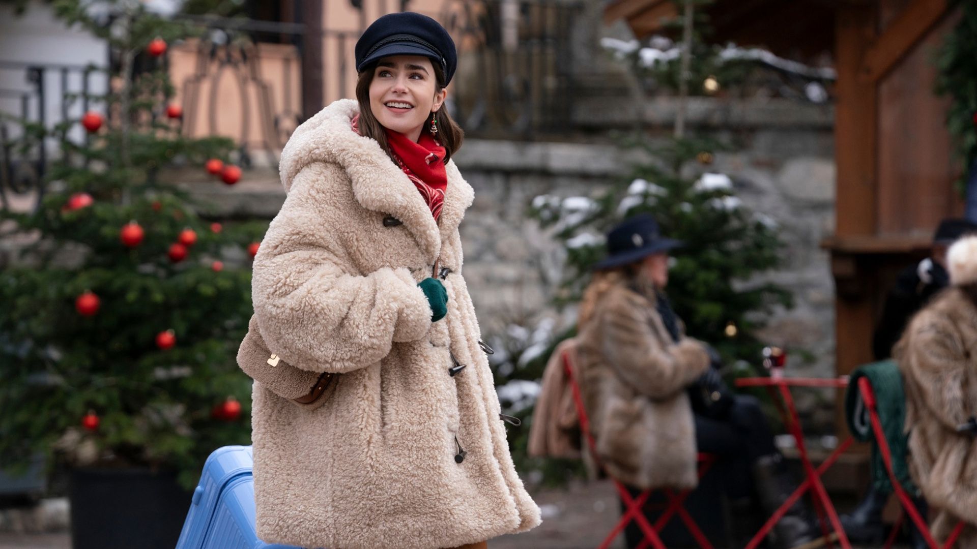 Emily walking down the street in a big coat smiling in Emily in Paris