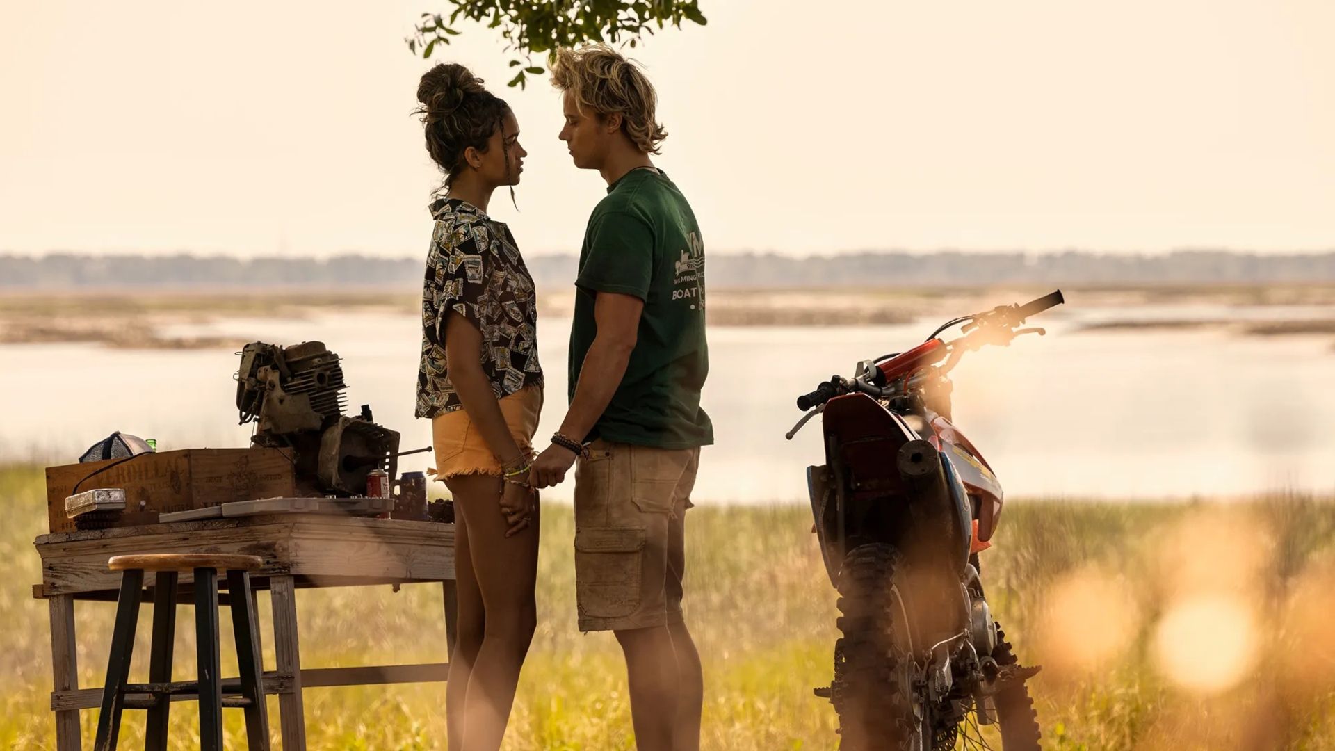 Madison Bailey and Rudy Pankow standing close in a field in Outer Banks