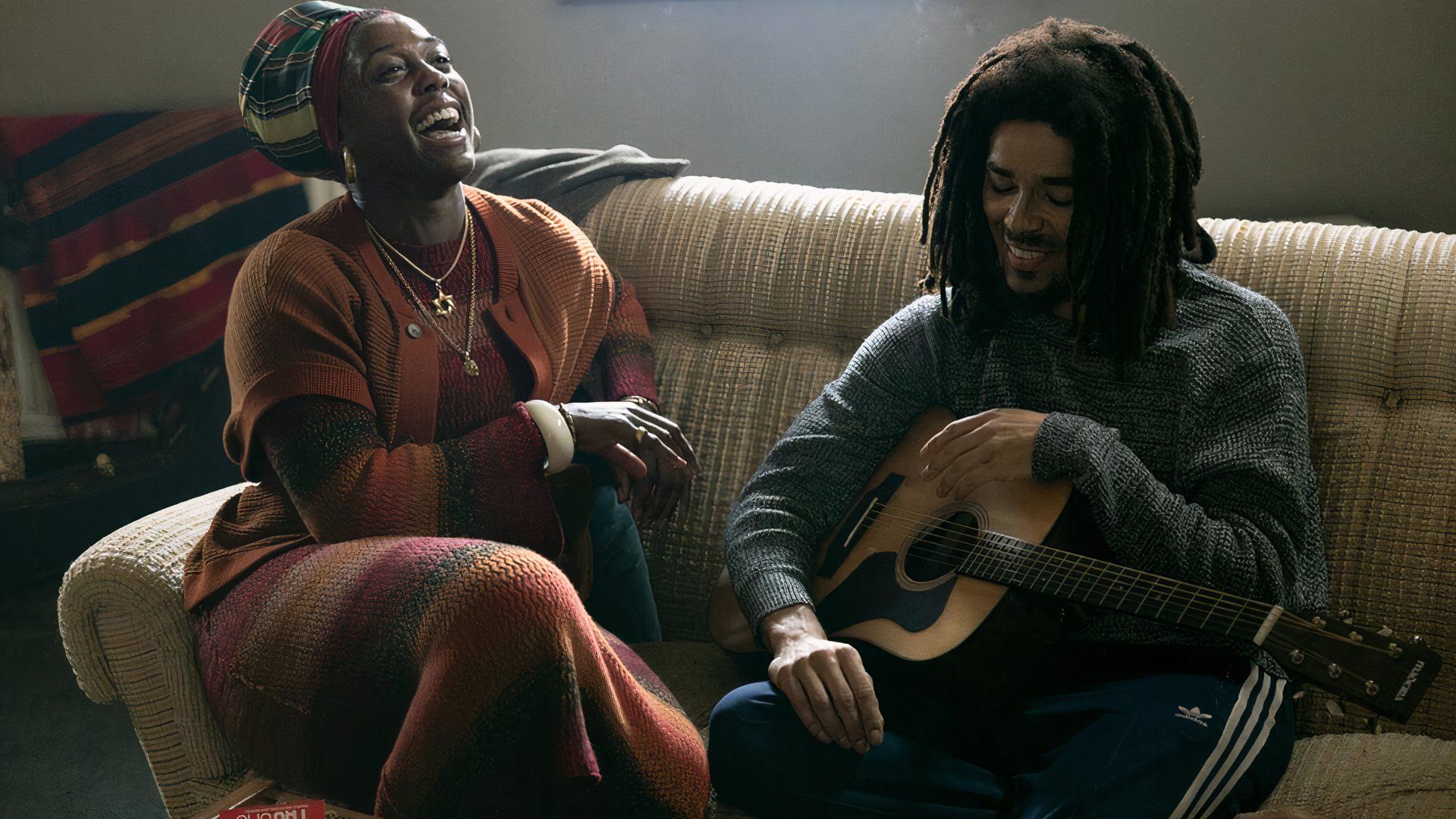 Rita and Bob laughing on the couch in Bob Marley: One Love