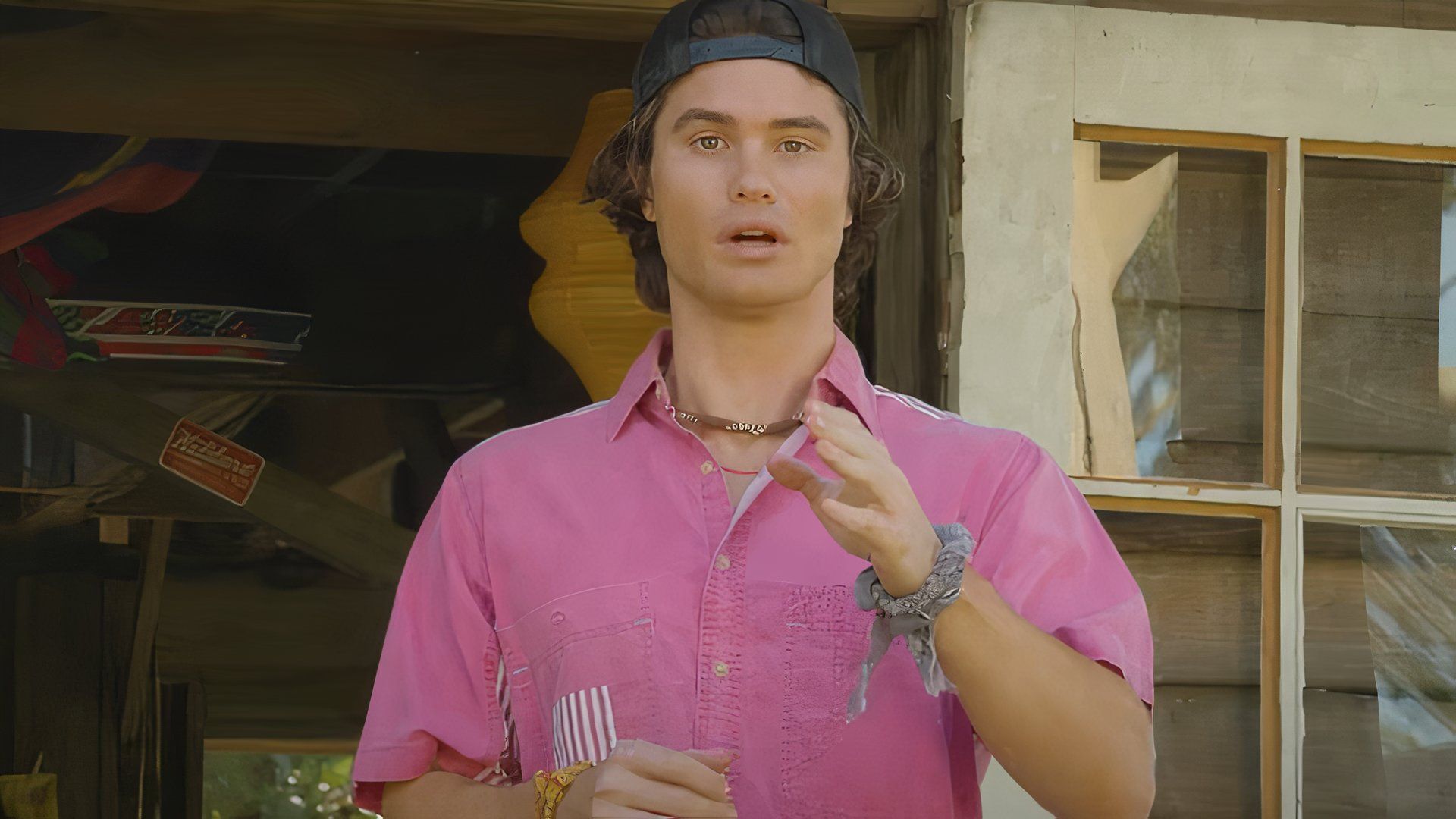 Chase Stokes in Outer Banks wearing a pink collared shirt