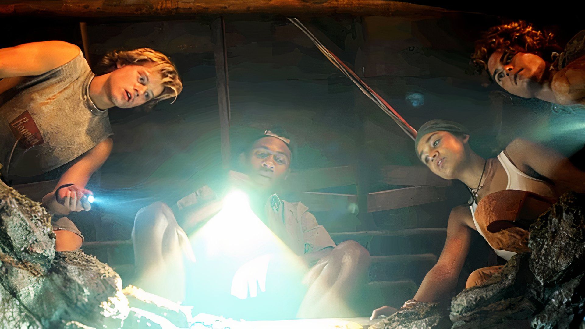 Rudy Pankow, Jonathan Daviss, Madison Bailey, and Chase Stokes shining a flashlight into a well in Outer Banks