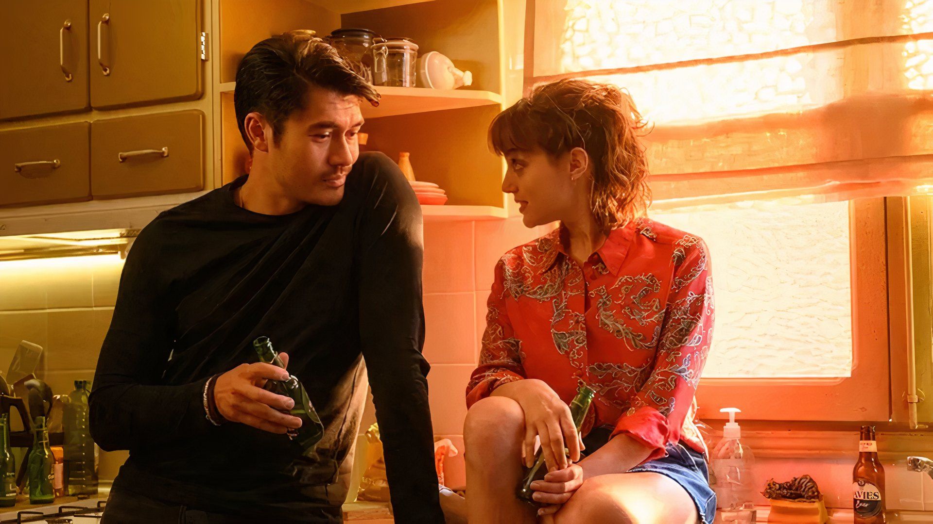 A man and a woman in a bright kitchen drink beer in Daniela Forever