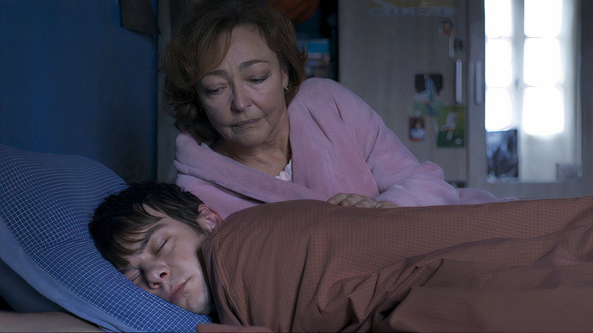 A woman in bed with a boy in the 2024 TIFF movie Misericordia