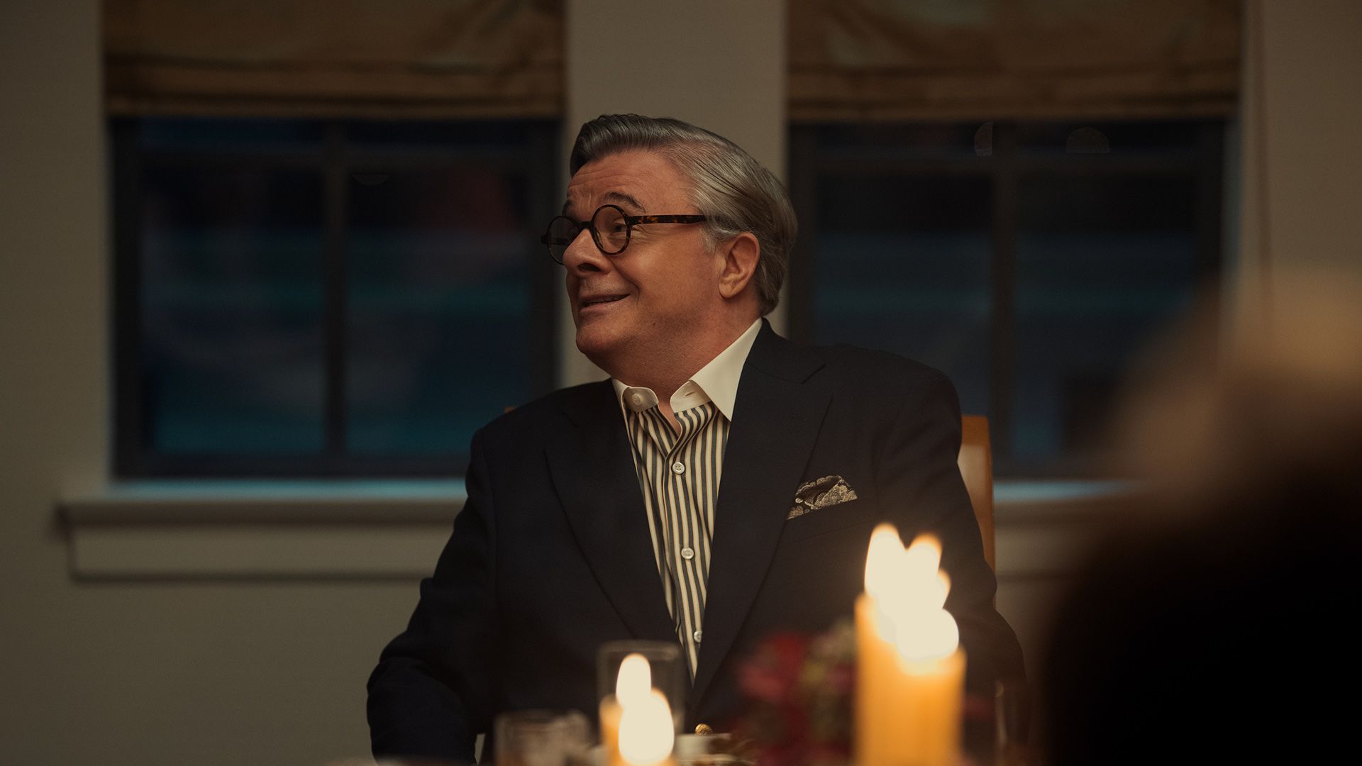 Dominick Dunne smiling at a dinner party with candles in front of him on Monsters.