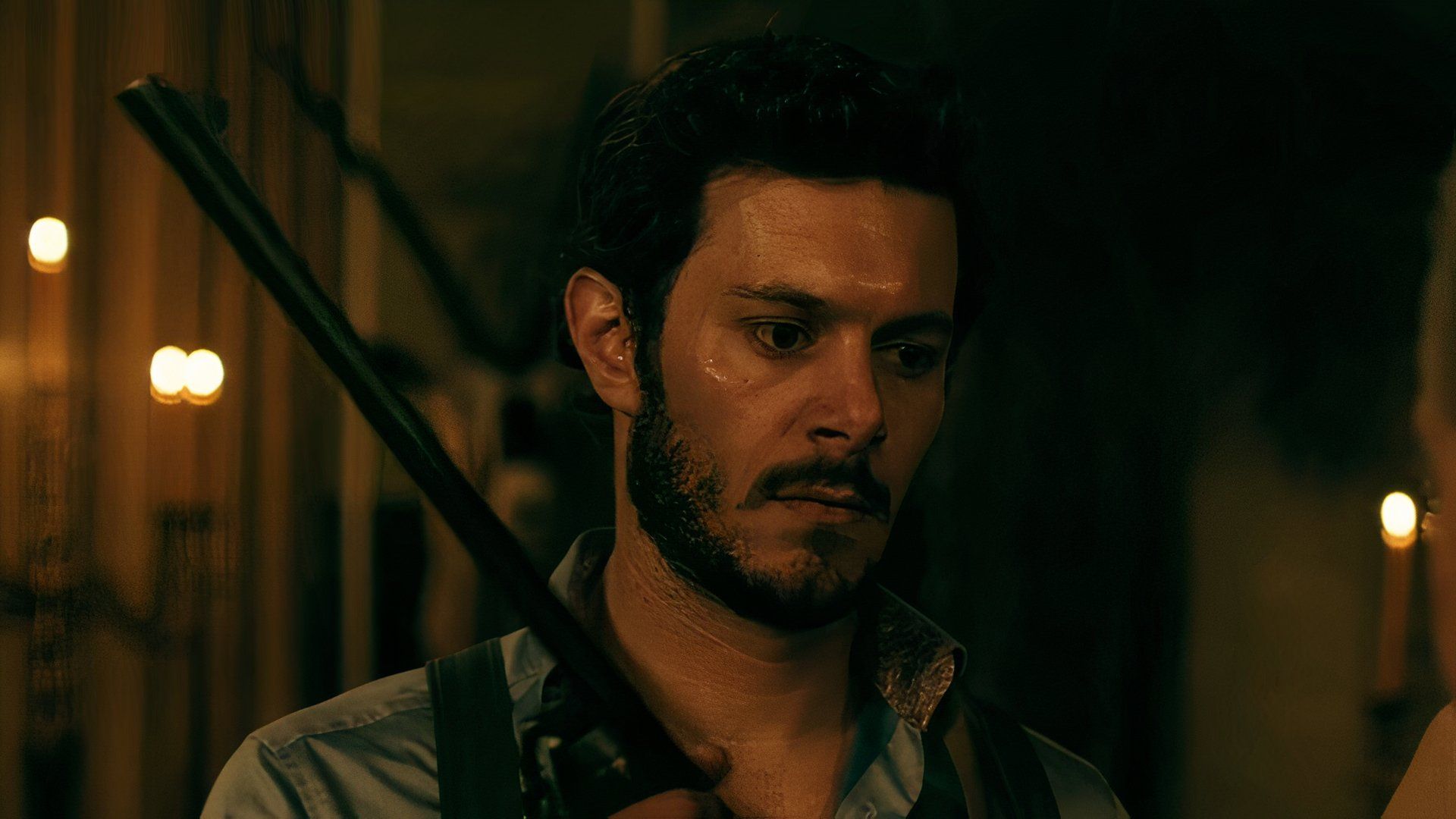 Adam Brody holding a gun in Ready or Not looking off-screen