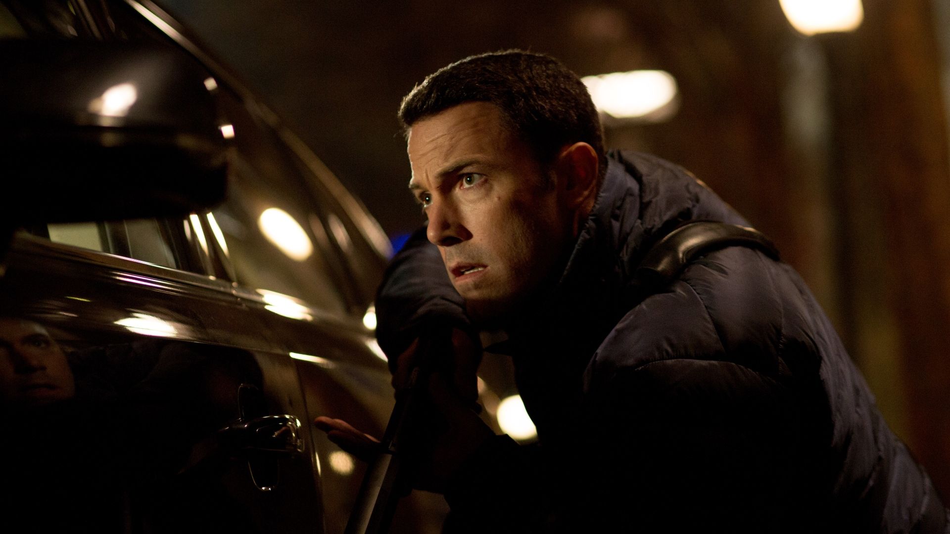 Ben Affleck in The Accountant hiding beside a car