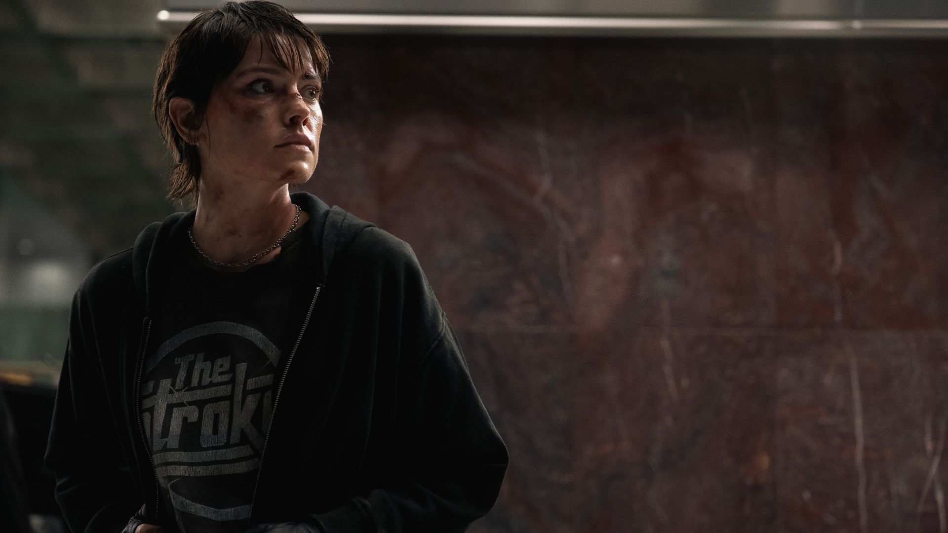 Daisy Ridley in a Strokes T-Shirt and bruised in the 2025 movie Cleaner