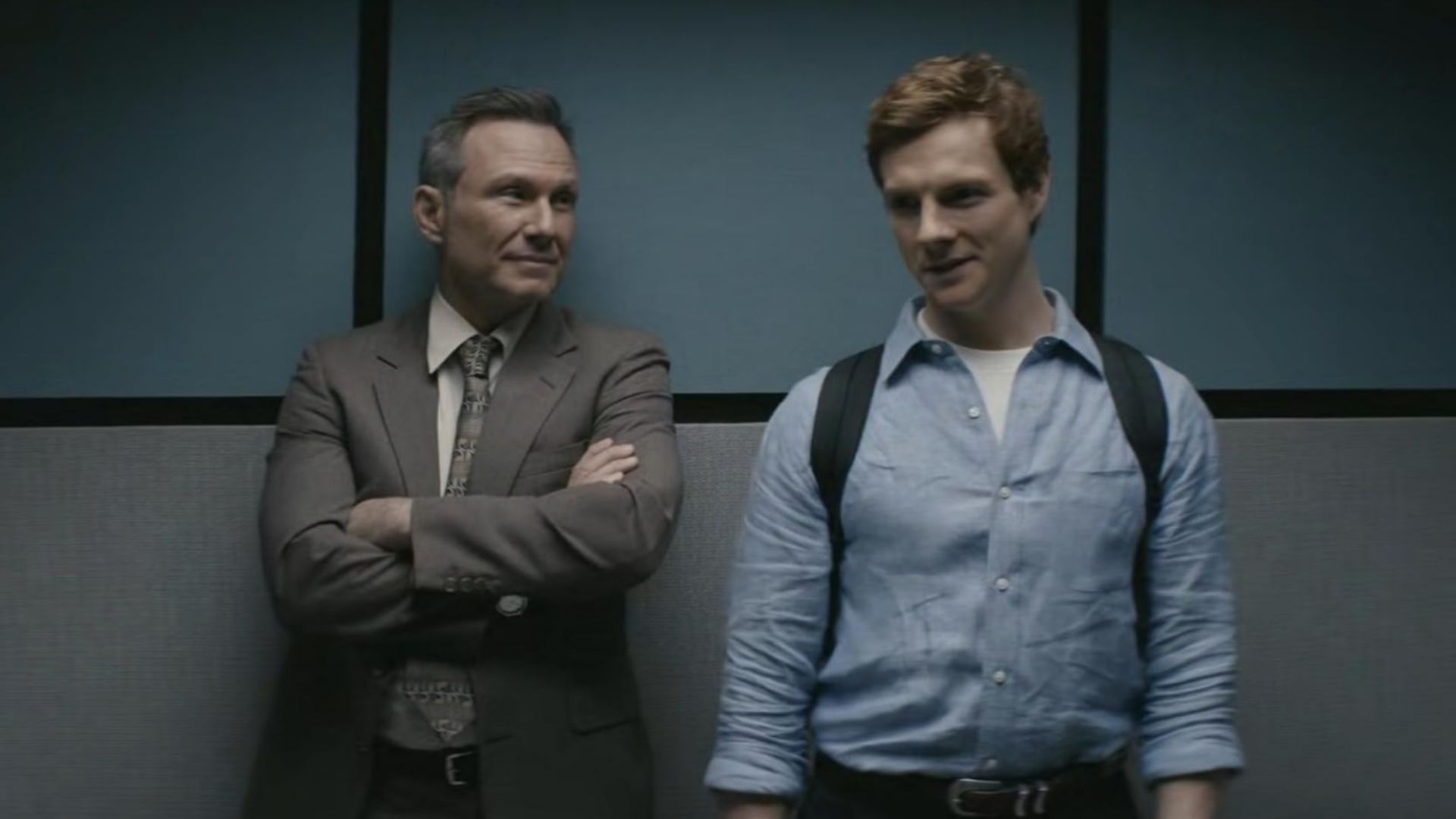 Harry with his arms folded looking at Dexter who is smiling with a backpack in Dexter: Original Sin.