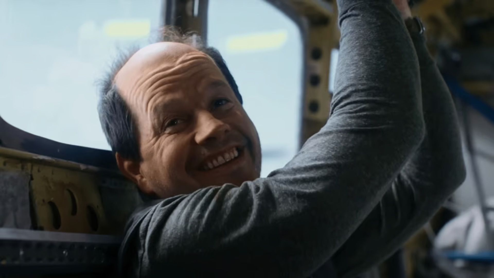 Mark Walhberg smiles in a bald cap in Flight Risk