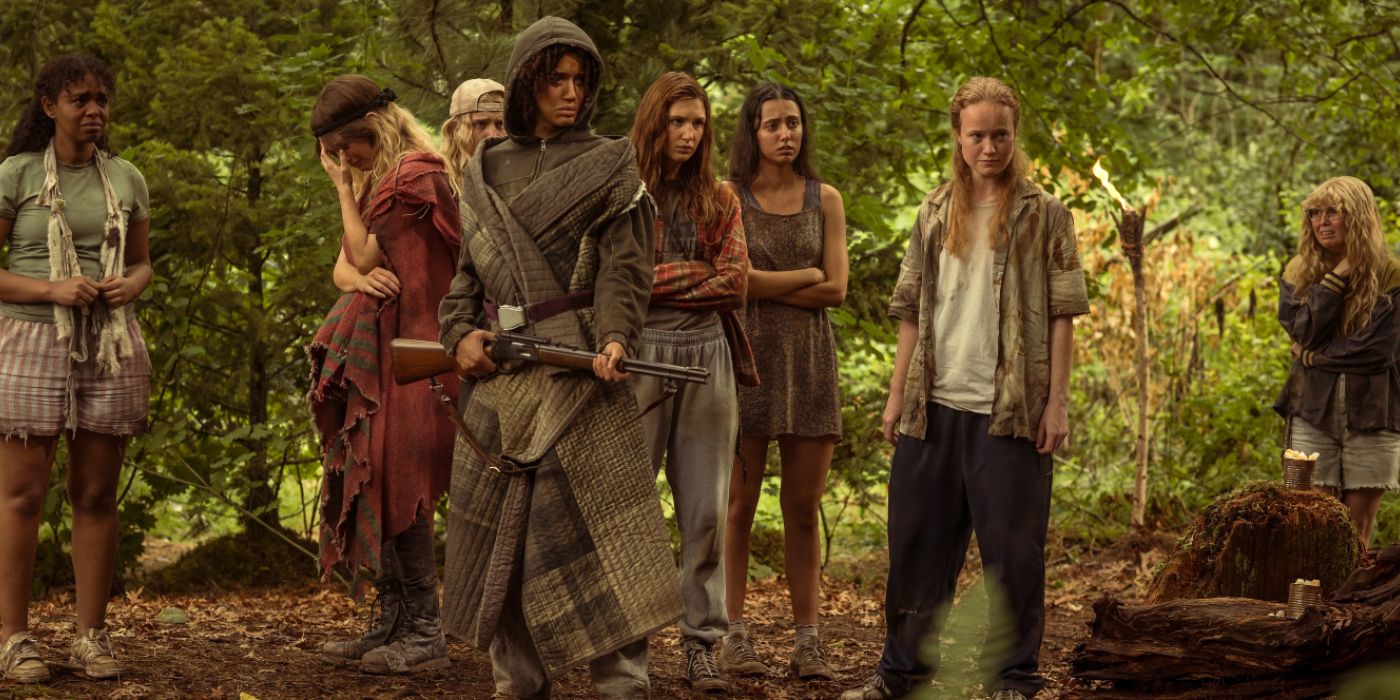 A group of young women in the woods with one girl holding a rifle in Yellowjackets