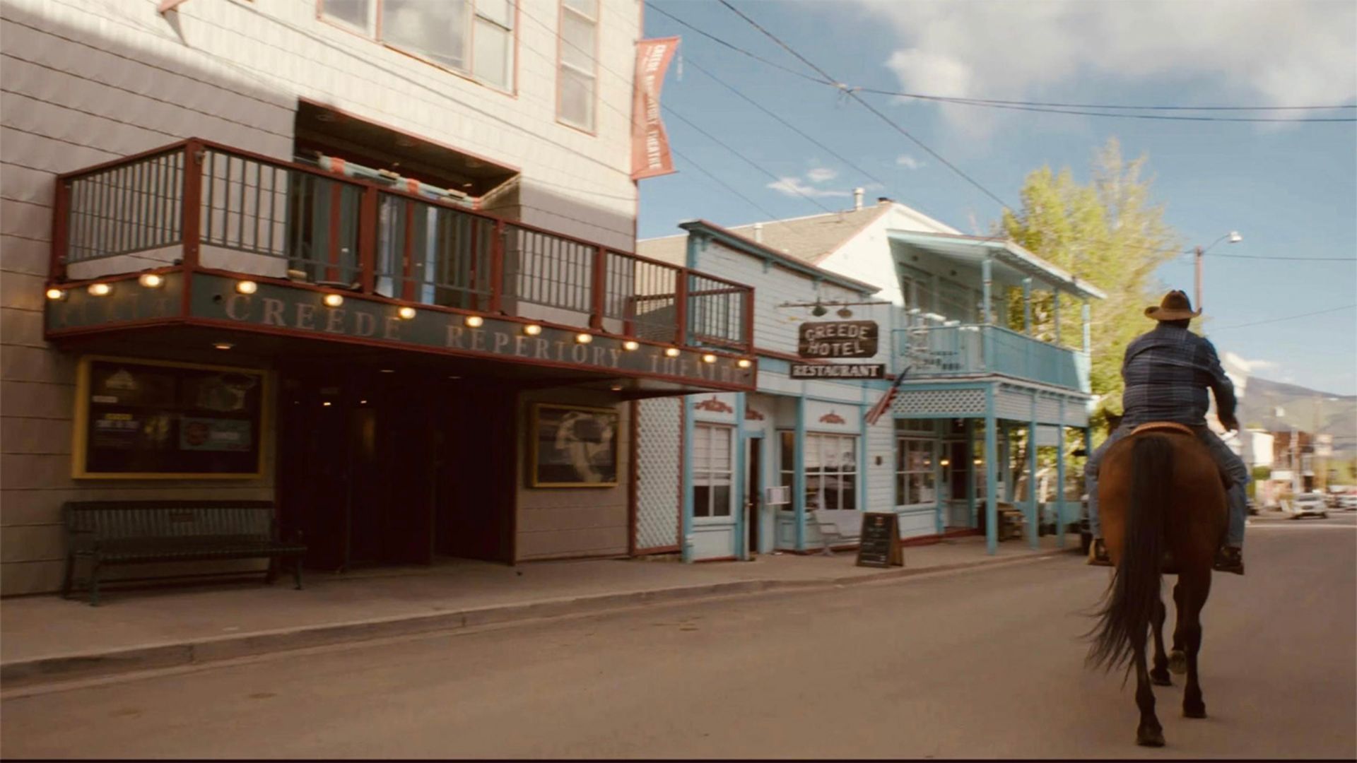 A man rides a horse through town in the movie Creede USA