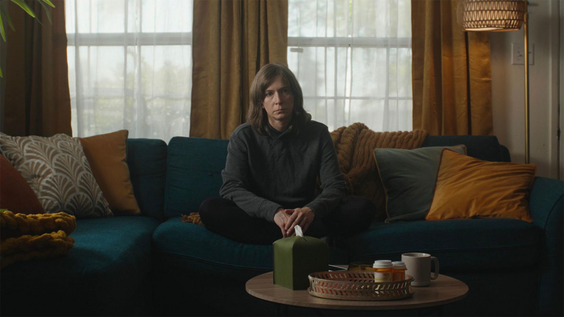 A person sits alone on the couch in the short film Out for Delivery