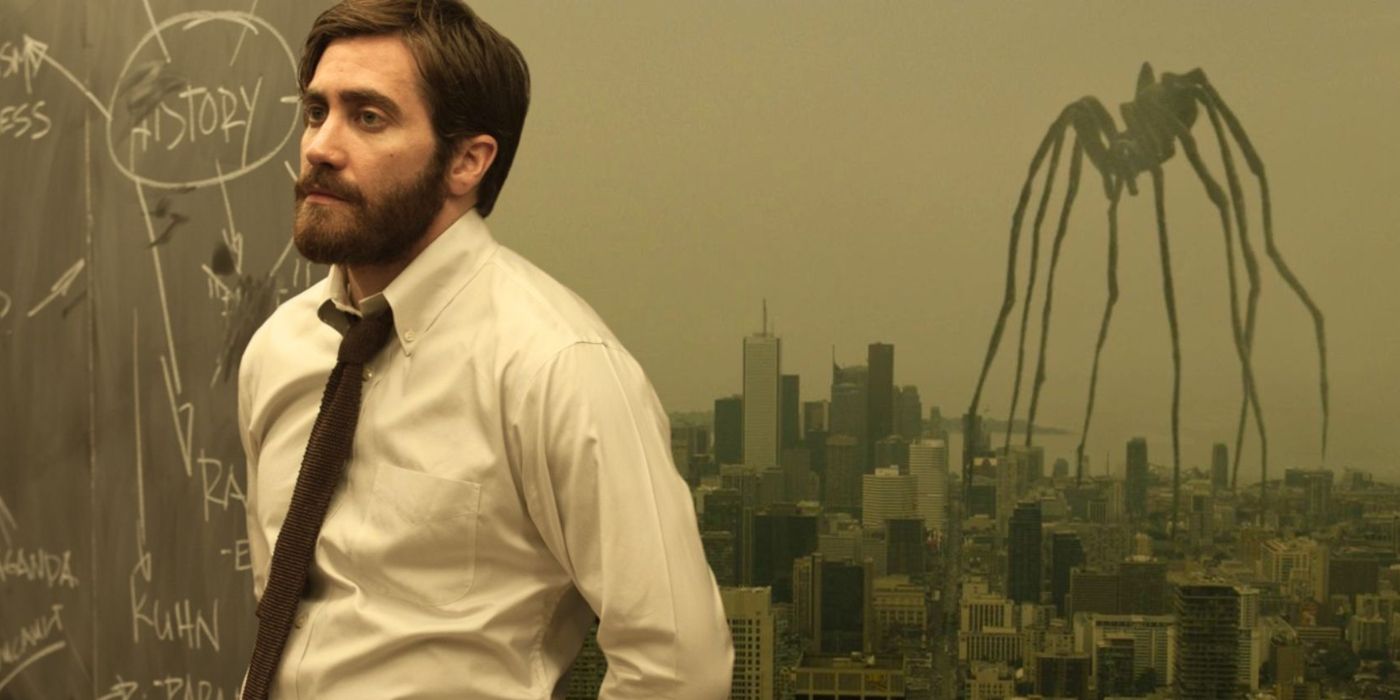 An edited image of Jake Gyllenhaal in Enemy standing next to a chalkboard with a giant spider in the background