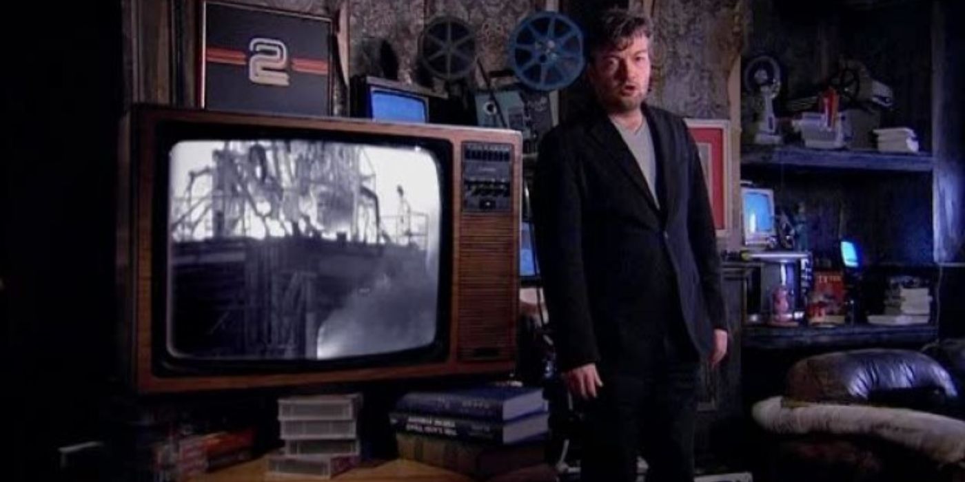 Charlie Brooker stands next to a big television in his show How TV Ruined Your Life