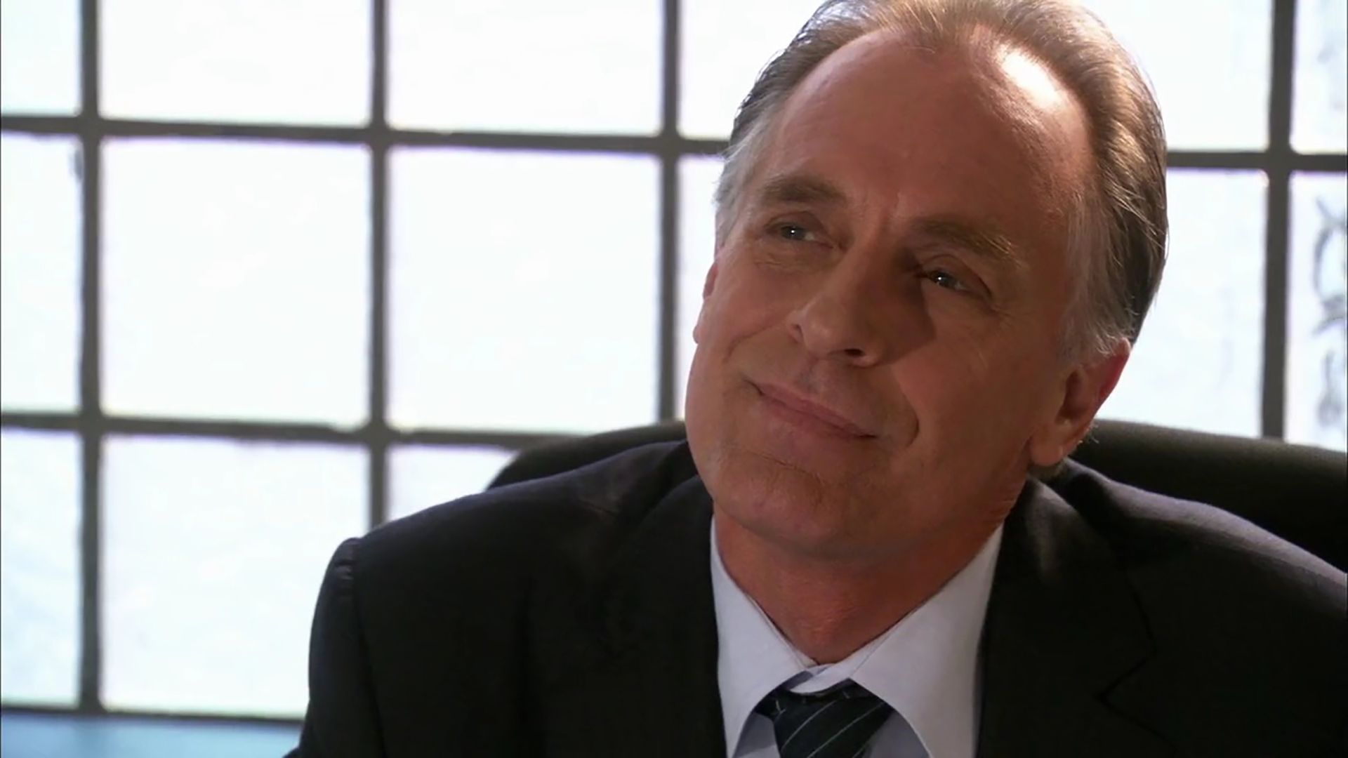 Lundy looking up from his desk with a suspicious smile in Dexter.