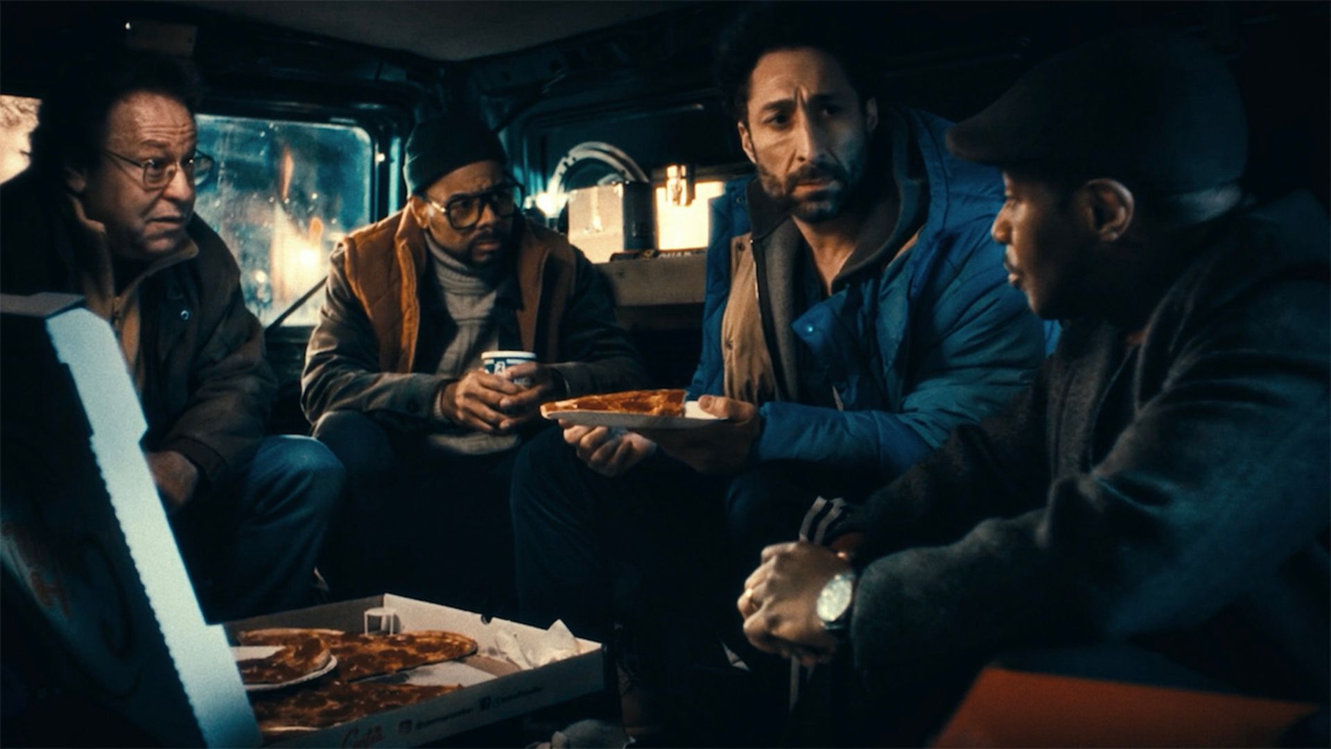 Men eat pizza in a van in the movie Caper