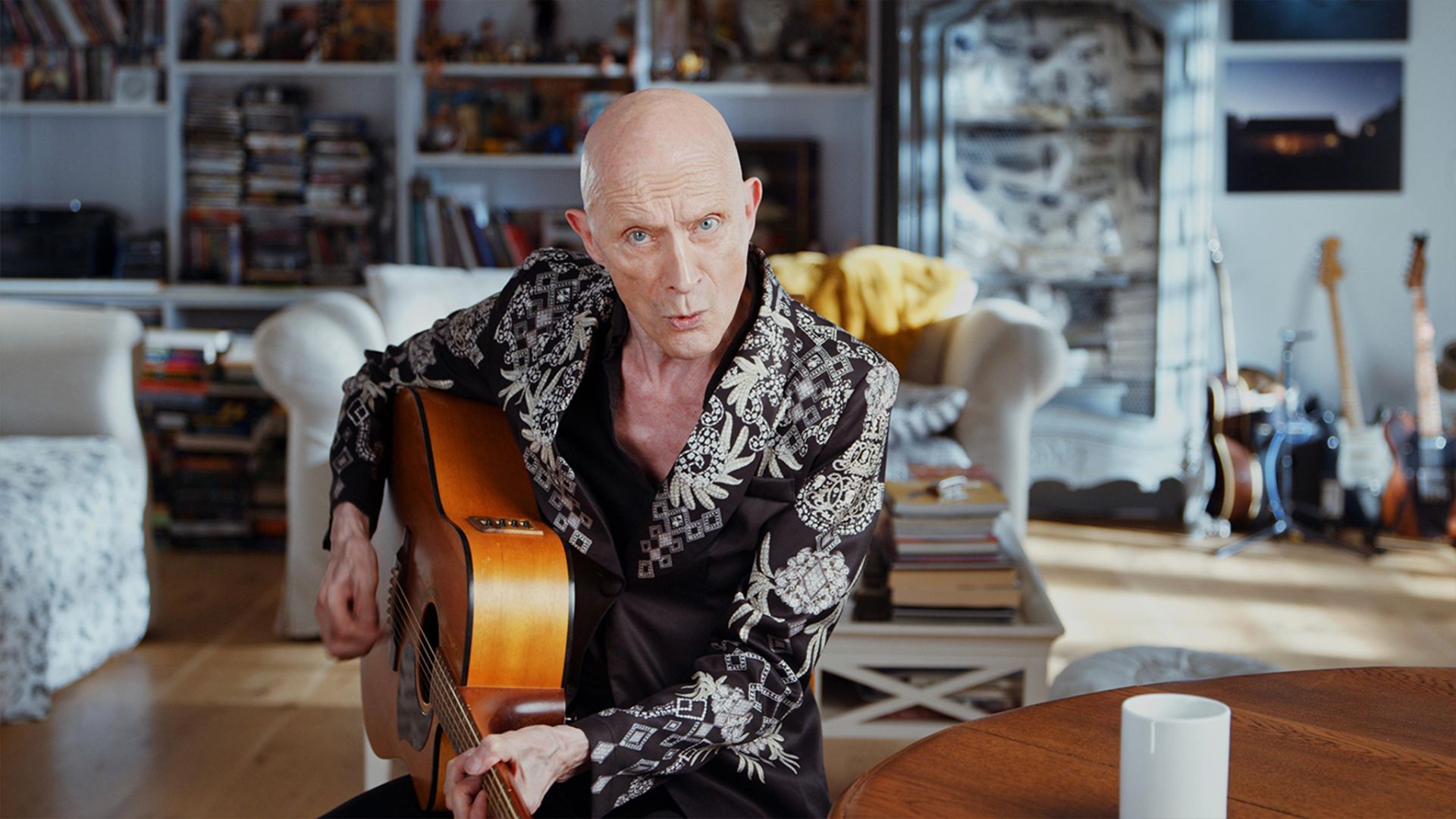 Richard O'Brien holds a guitar in Strange Journey - The Story of Rocky Horror