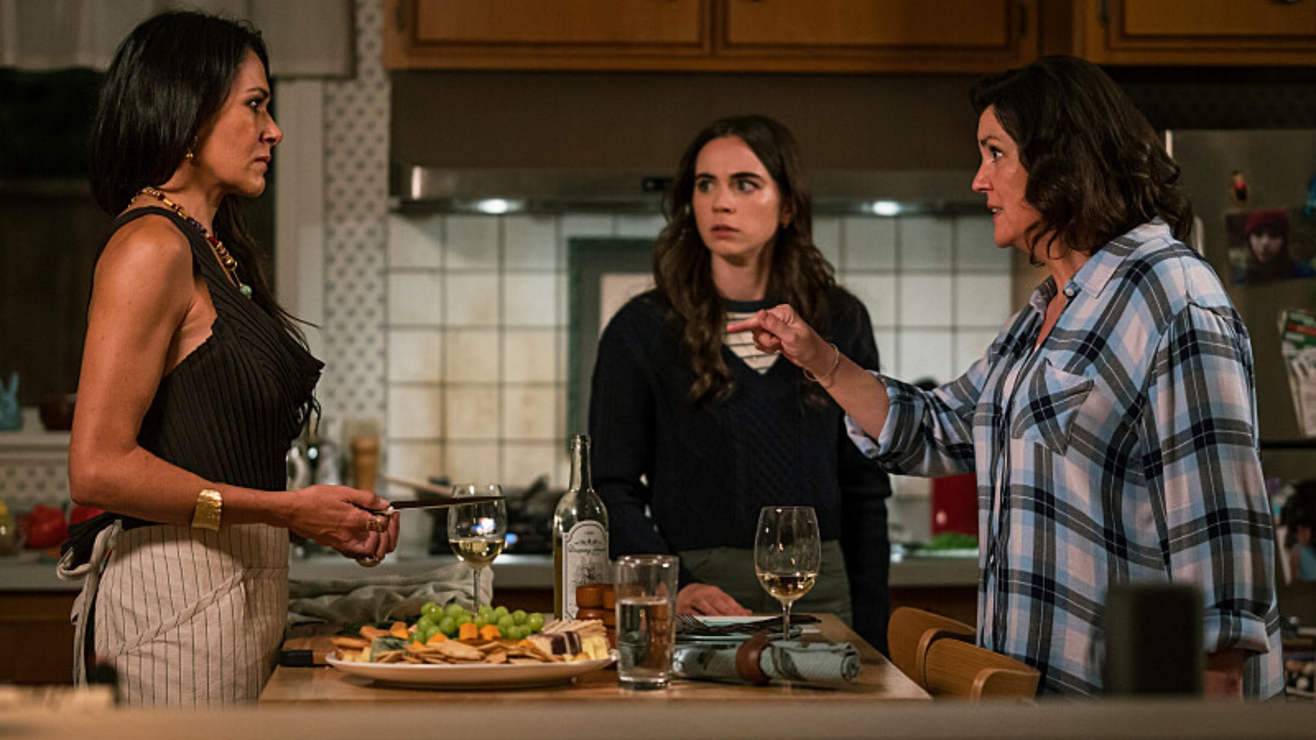 Lottie and Shauna arguing in the kitchen as Callie looks on in Yellowjackets.