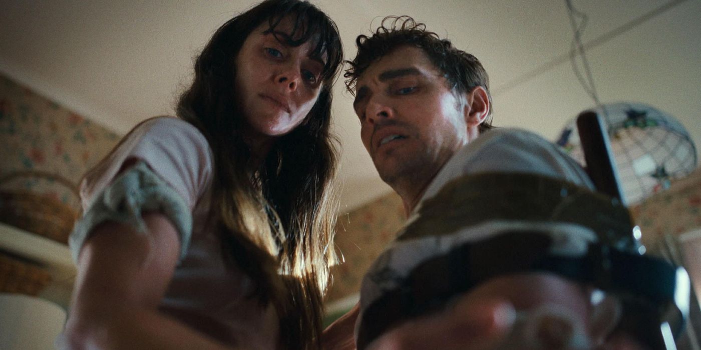 Alison Brie and Dave Franco looking down beneath the chair in the 2025 movie Together