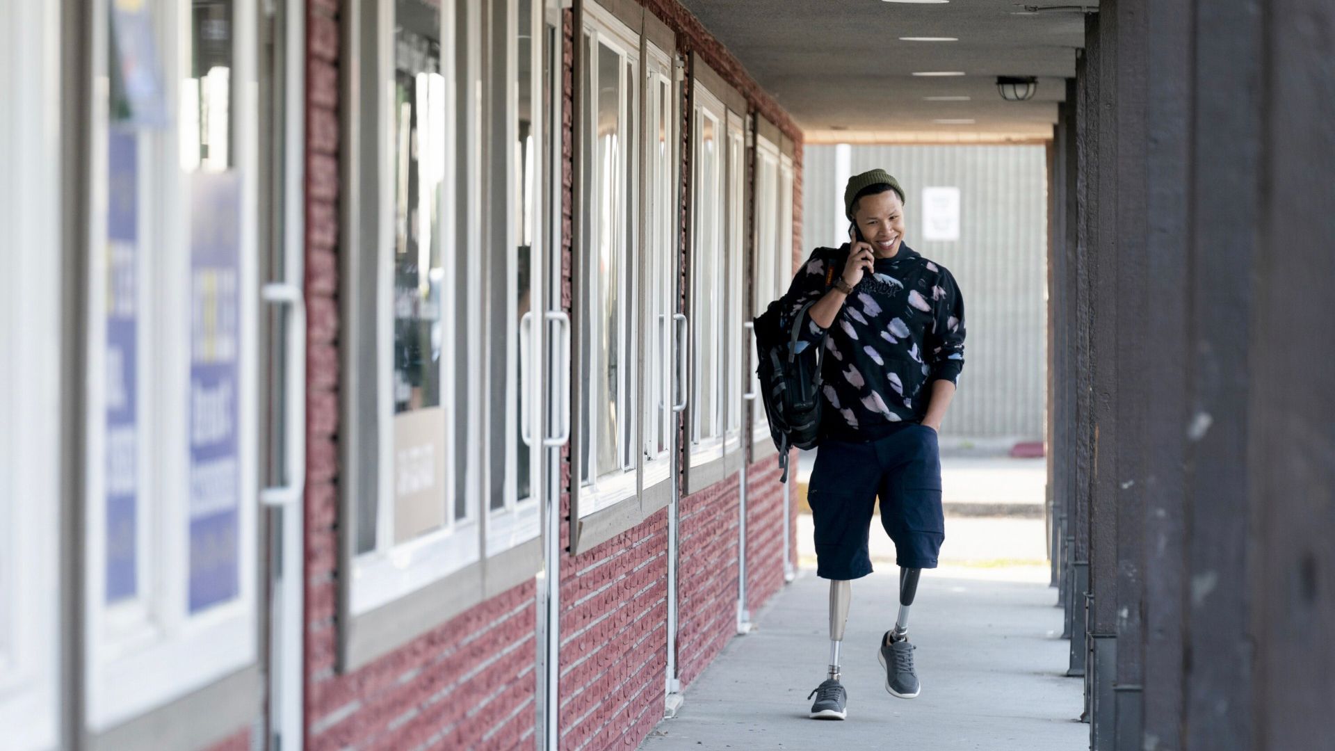 Bobby walking alongside a building on the phone and smiling in Tracker.