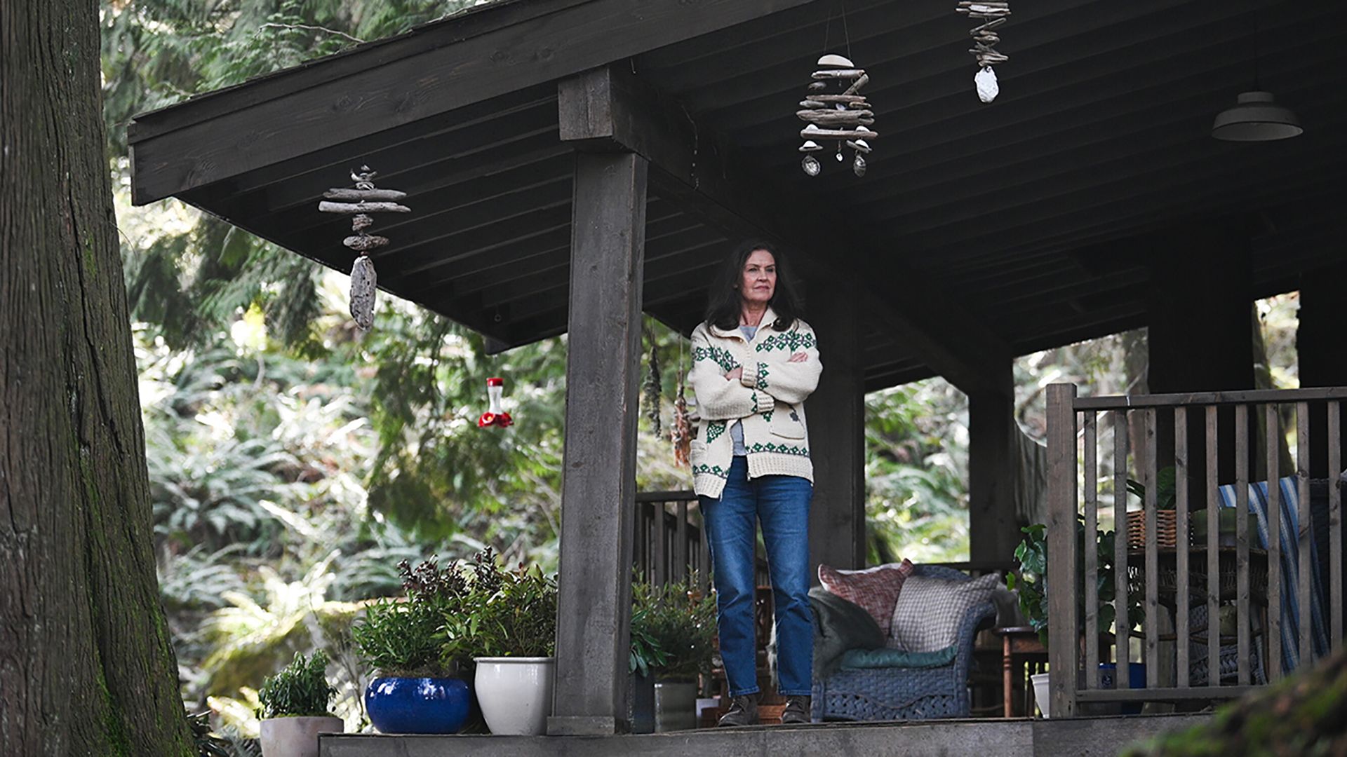 Mary standing on her porch with her arms folded in Tracker.