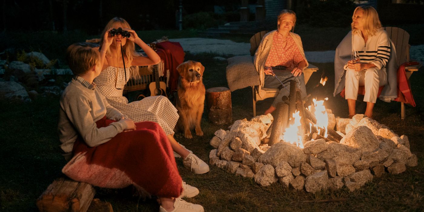 Emily Alyn Lind as Cady looking through binoculars while at a camp fire in We Were Liars