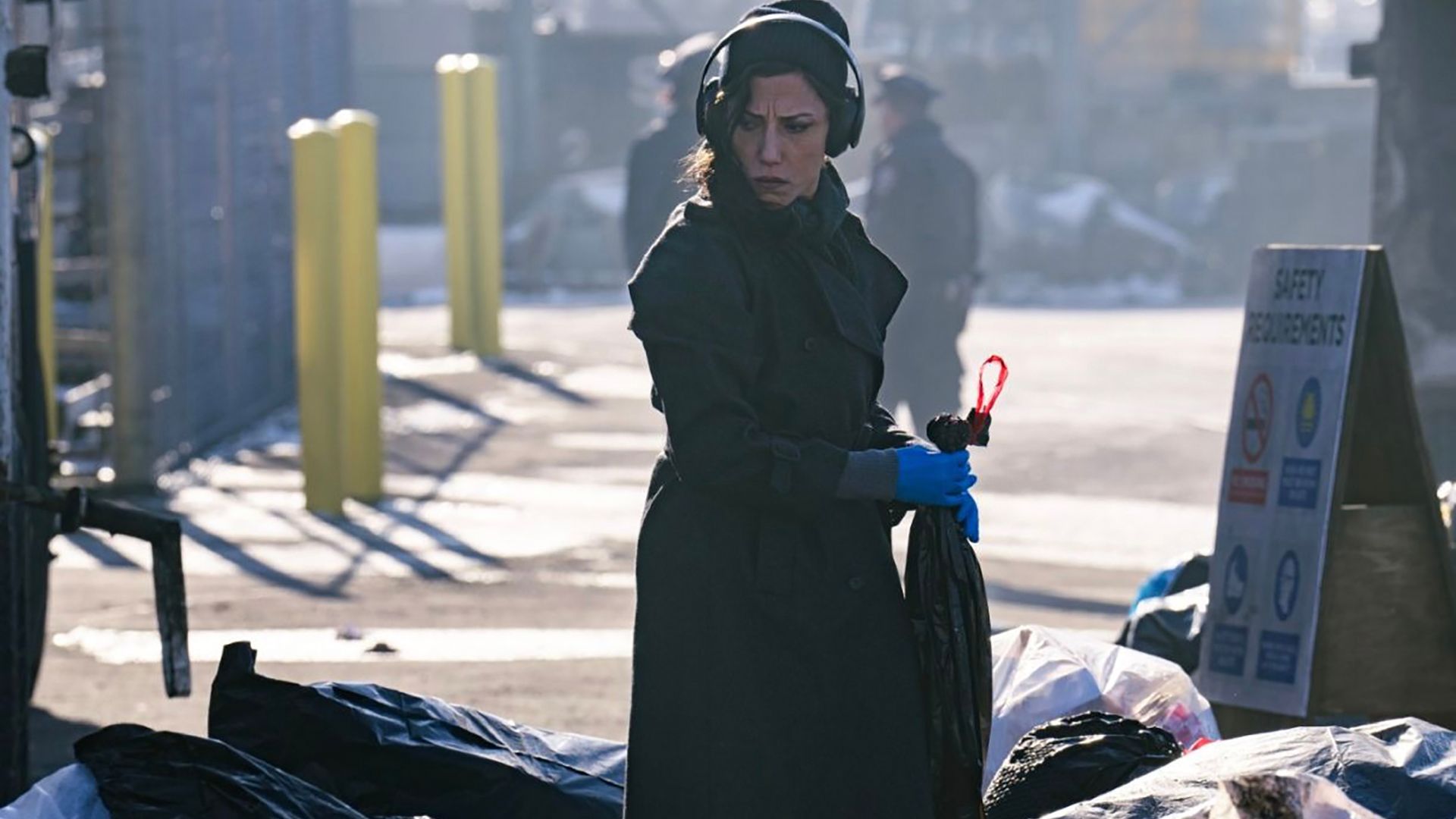 Claudette wearing headphones, holding a garbage bag in Dexter: Resurrection.